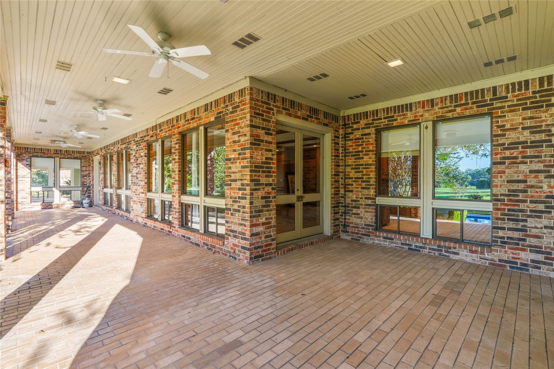 218 Bella Vista Drive, Richmond, TX 77406 Expansive covered patio with brick flooring and ceiling fans, offering a perfect space for outdoor relaxation and entertaining.