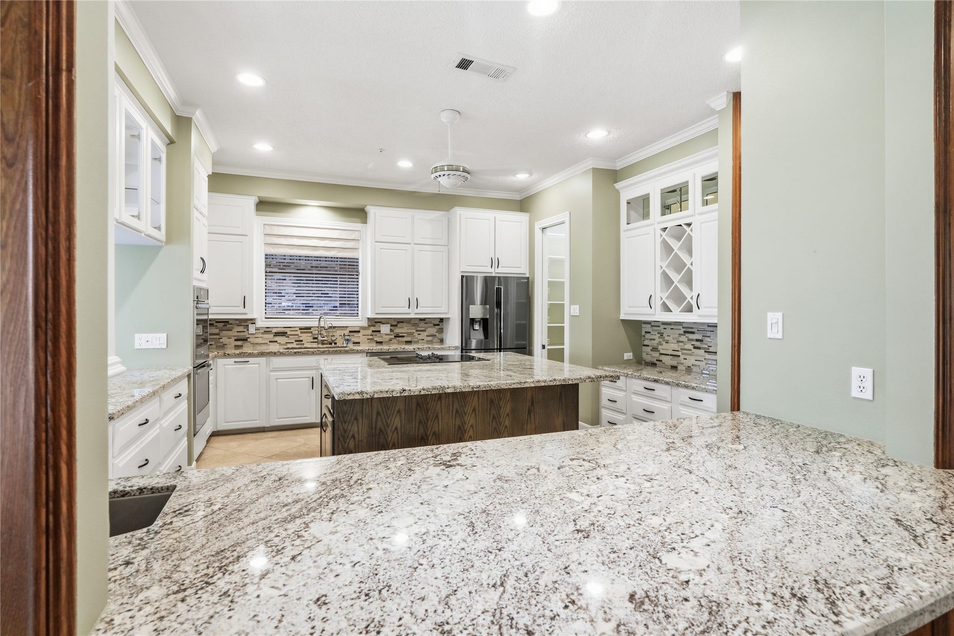 218 Bella Vista Drive, Richmond, TX 77406 Spacious kitchen with granite countertops, white cabinetry, a central island, and modern stainless steel appliances, perfect for culinary enthusiasts.