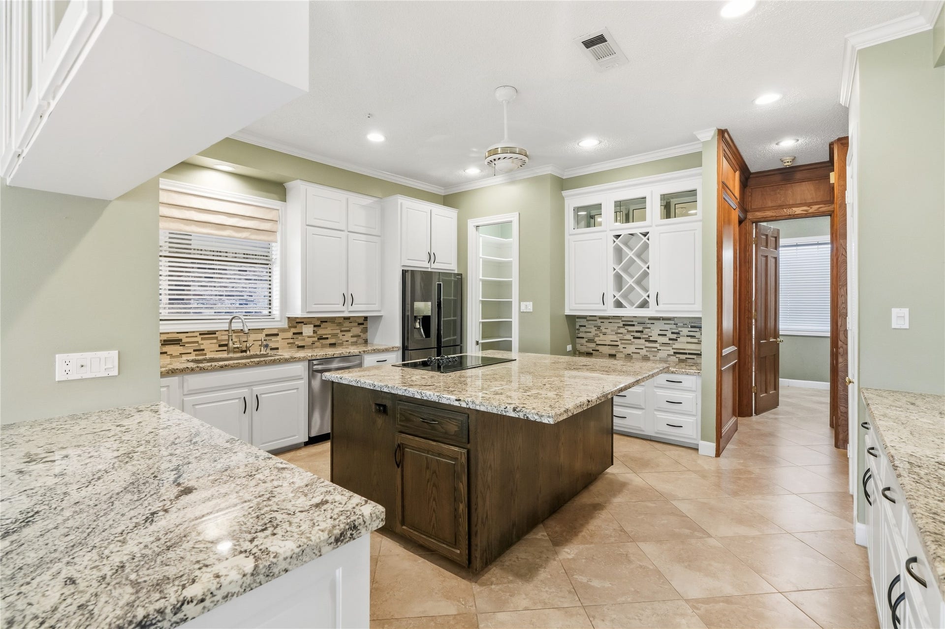 218 Bella Vista Drive, Richmond, TX 77406 Spacious kitchen featuring sleek granite countertops, a center island, and ample cabinetry with stylish glass fronts.