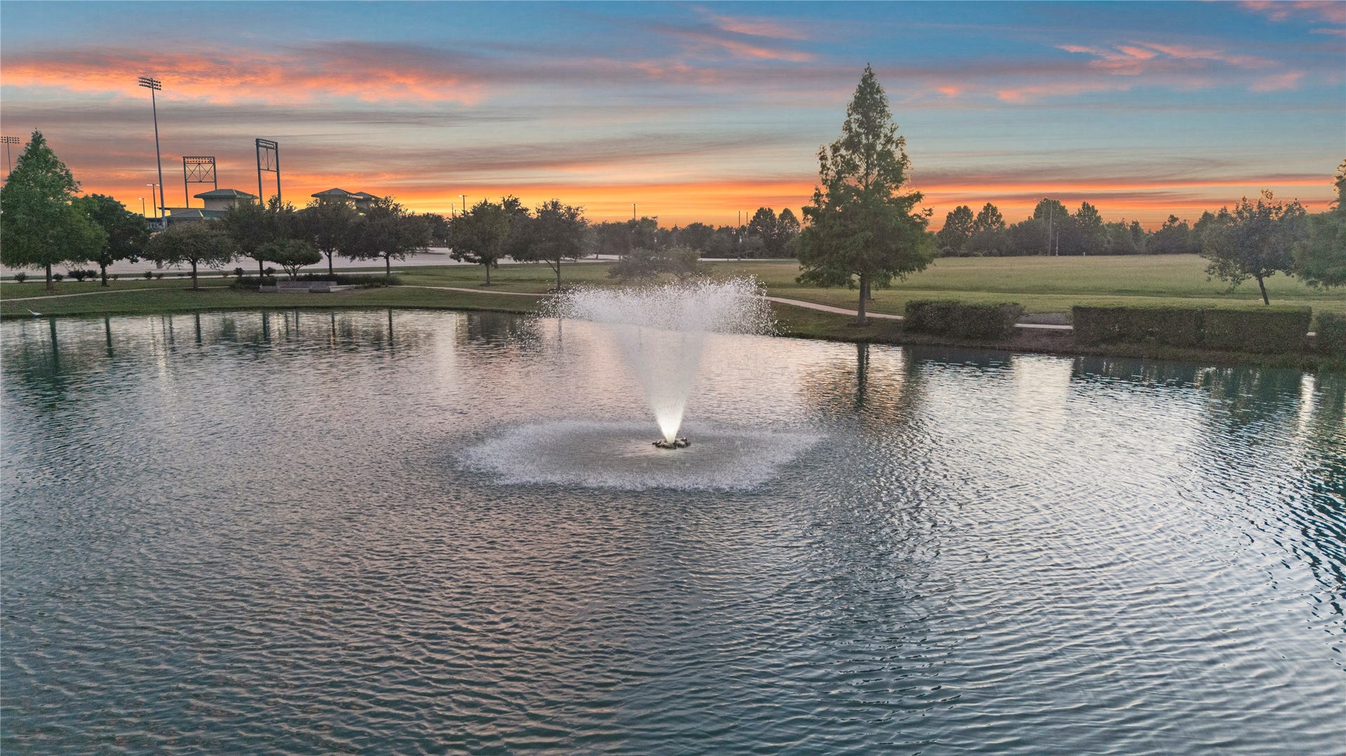 11 Victorian Run, Sugar Land, TX 77498 A breathtaking sunset reflects across the tranquil lake, where elegant fountains and lush green surroundings create a peaceful escape right in the heart of the community.