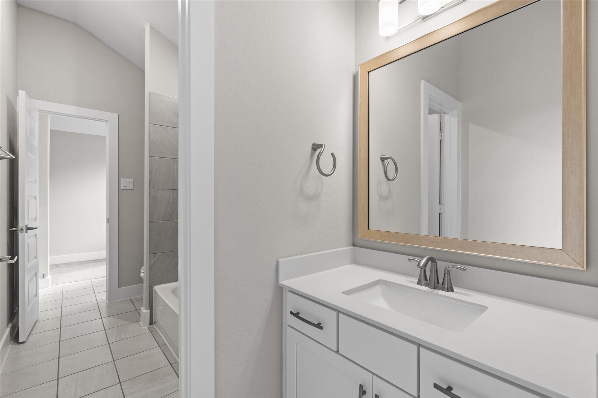 11 Victorian Run, Sugar Land, TX 77498 Well-appointed bathroom featuring a sleek single-sink vanity with quartz countertop, modern fixtures, and a framed mirror. The layout flows seamlessly into the adjacent bathing area, offering both style and everyday convenience.