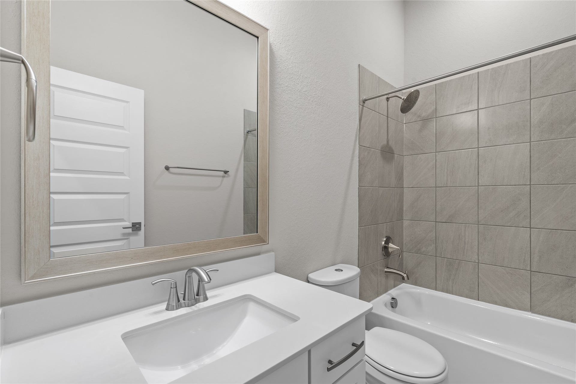 11 Victorian Run, Sugar Land, TX 77498 Secondary bathroom featuring a clean, modern design with a quartz countertop vanity, framed mirror, and tiled tub/shower combination. Neutral finishes create a fresh and inviting space for guests or family use.