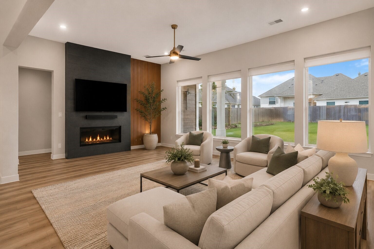 11 Victorian Run, Sugar Land, TX 77498 Spacious living area with soaring ceilings, expansive windows for abundant natural light, and a sleek Spanish-tiled fireplace with a designer accent wall. The open layout and warm wood-look flooring create an inviting space perfect for relaxing and entertaining.
