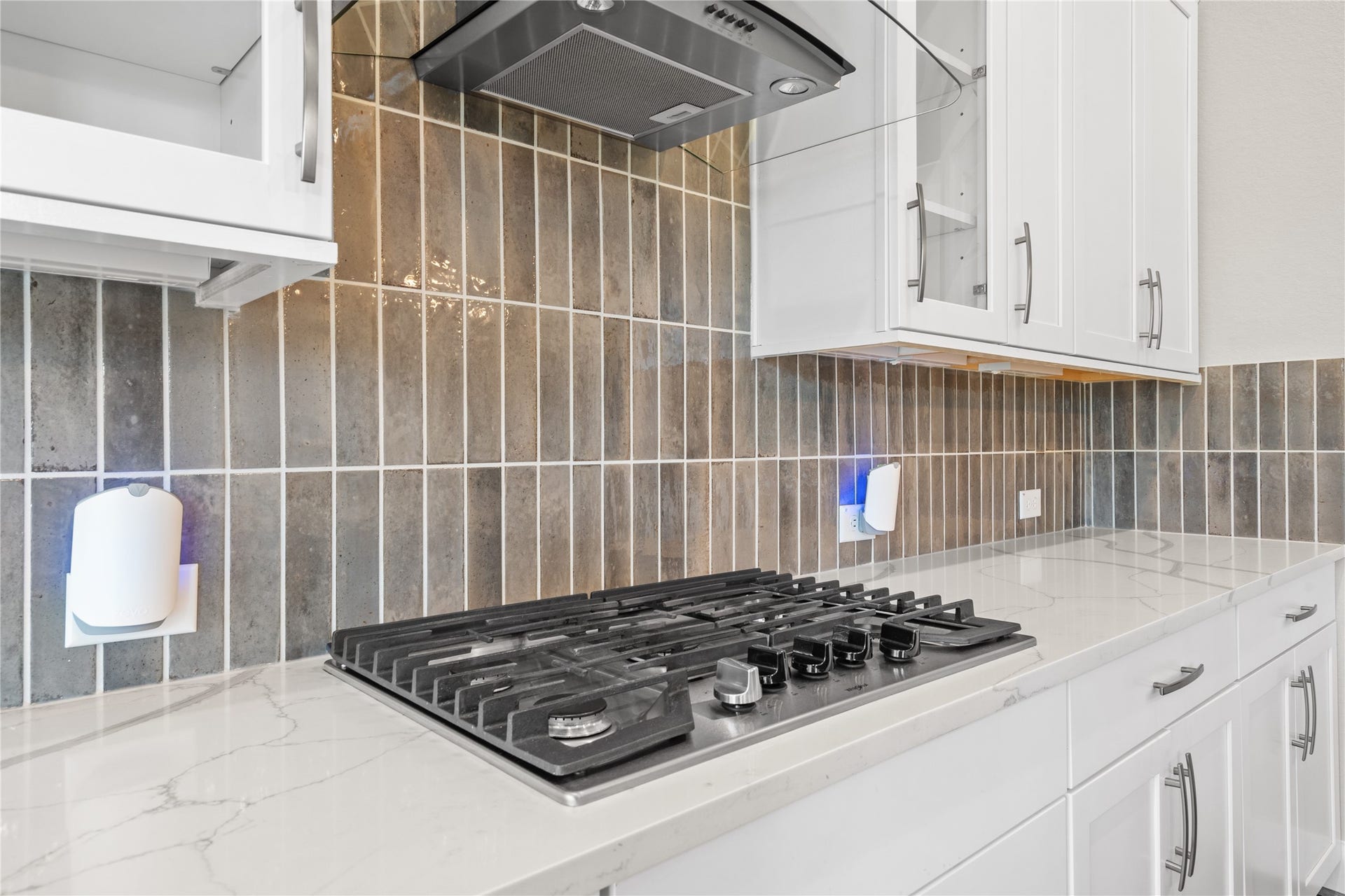 11 Victorian Run, Sugar Land, TX 77498 Close-up of the gourmet kitchens gas cooktop set into elegant quartz countertops, paired with a stylish vent hood and eye-catching tile backsplash. A perfect blend of functionality and modern design for everyday cooking.