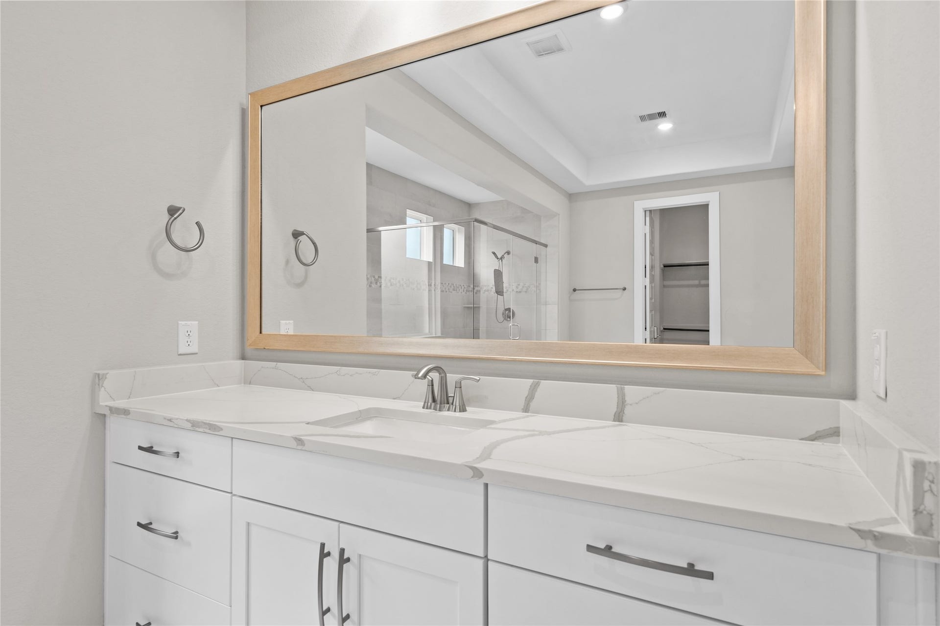 11 Victorian Run, Sugar Land, TX 77498 Elegant primary bathroom vanity featuring an extended quartz countertop with dual sink capability, sleek cabinetry, and modern fixtures. The large framed mirror enhances the space while providing a clean, contemporary look.