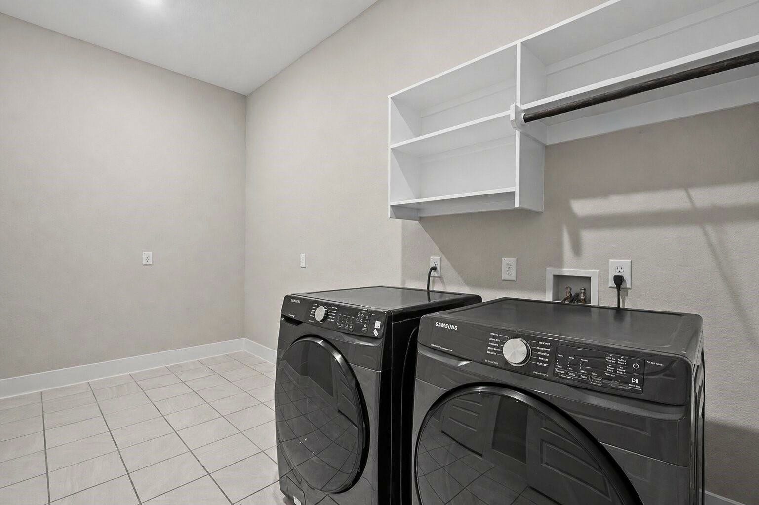 11 Victorian Run, Sugar Land, TX 77498 Spacious laundry room with modern washer and dryer, tile flooring, and built-in shelving for convenient storage and organization.