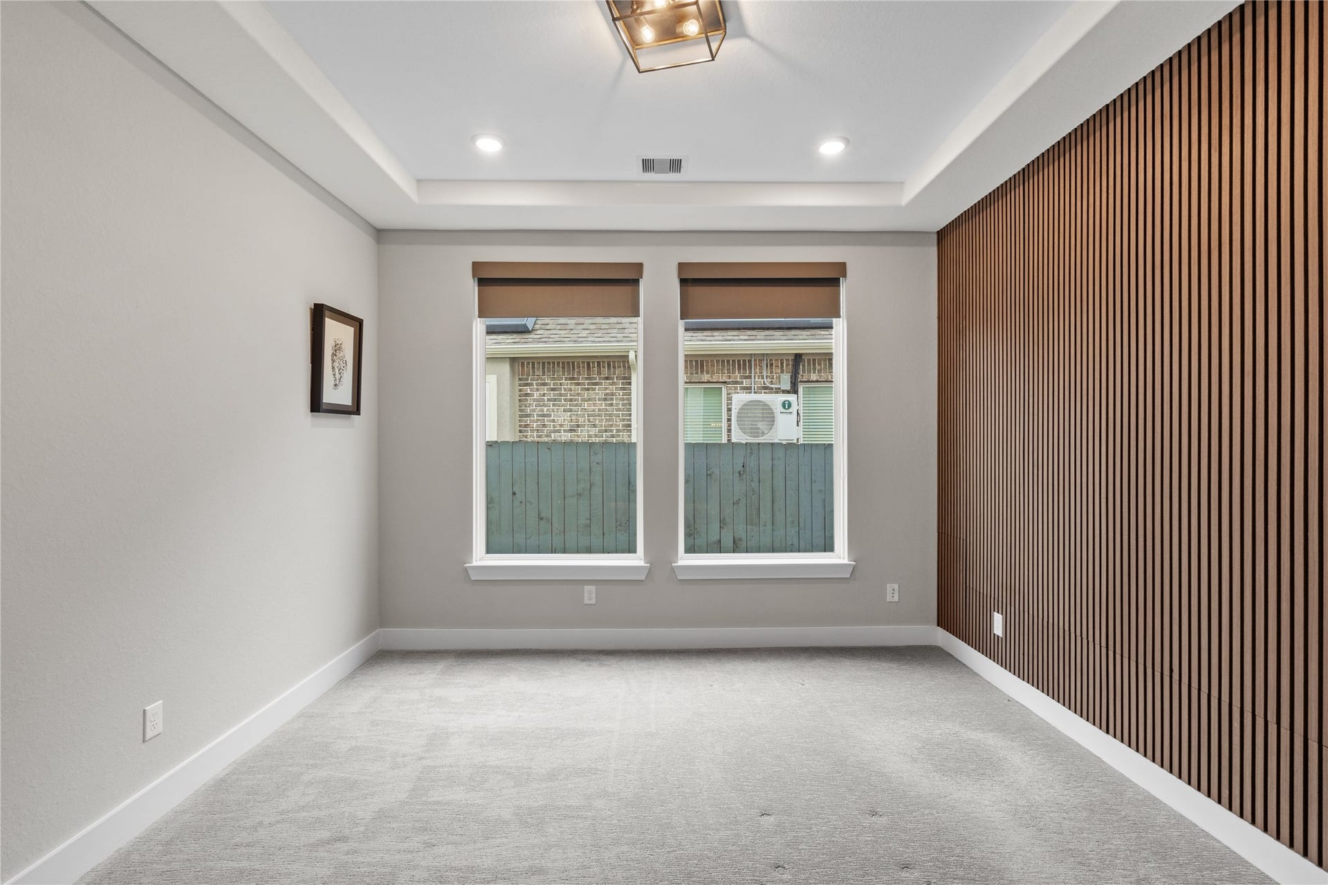 11 Victorian Run, Sugar Land, TX 77498 Bright and inviting room featuring a tray ceiling, recessed lighting, and dual windows for natural light, complemented by a modern wood accent wall.