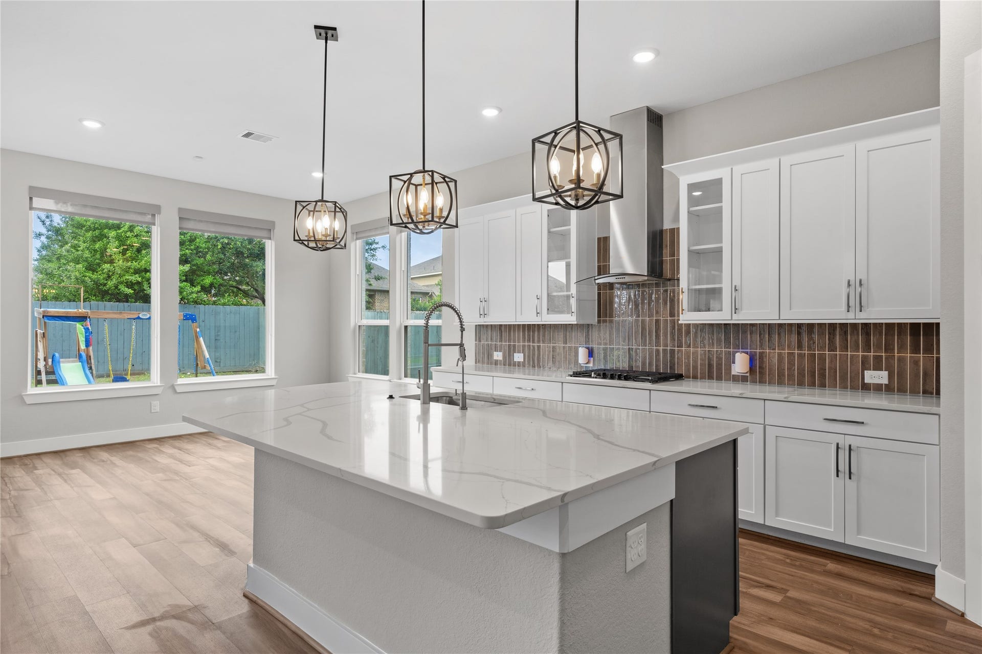 11 Victorian Run, Sugar Land, TX 77498 Beautifully appointed kitchen with an expansive island and deep undermount sink, complemented by a high-arc faucet and elegant pendant fixtures. The space is enhanced by abundant cabinetry, a stylish backsplash, and large windows that bring in natural light and backyard views.