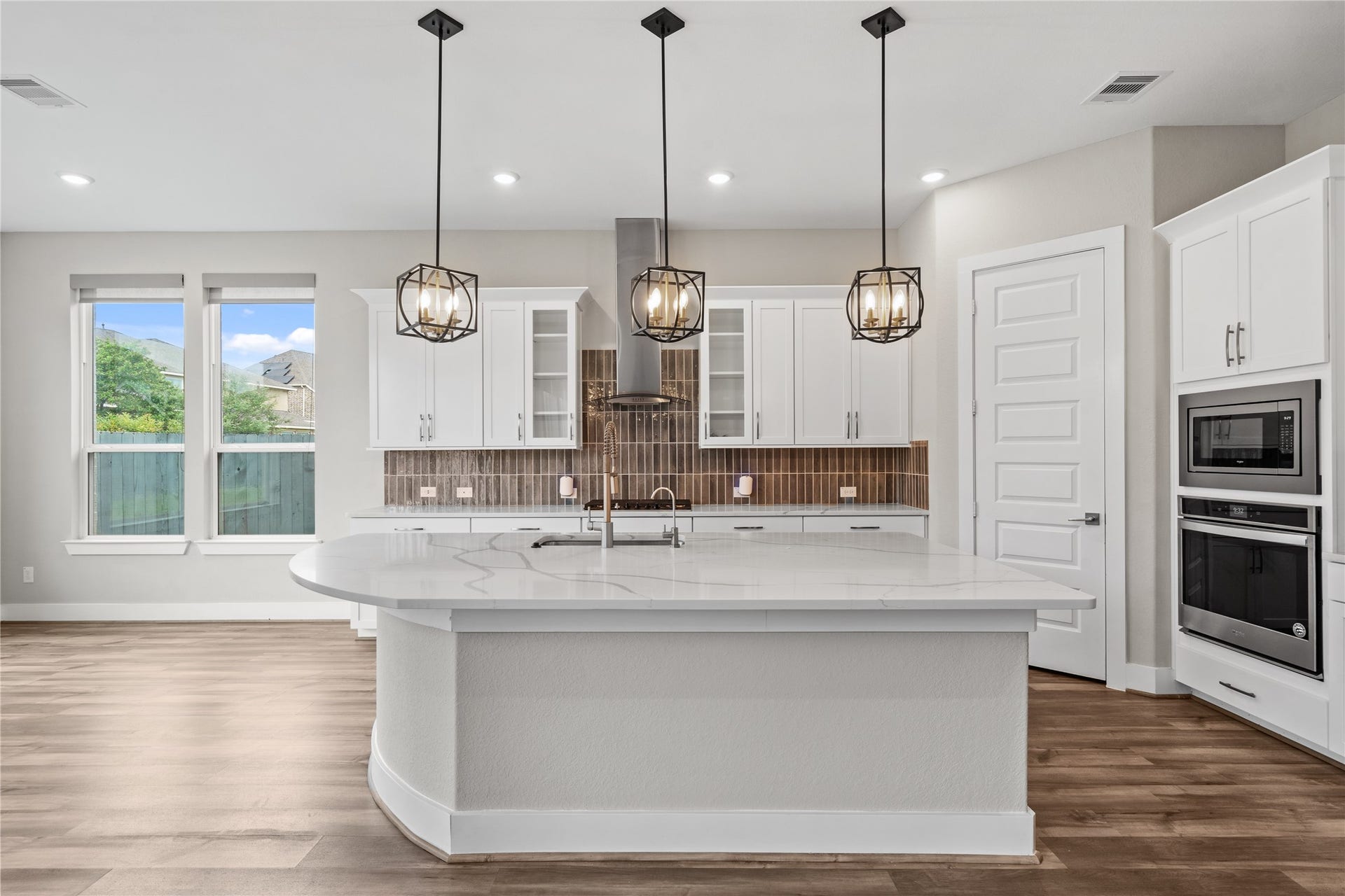 11 Victorian Run, Sugar Land, TX 77498 Oversized center island with sleek quartz countertops anchors this stunning kitchen, complemented by designer pendant lighting and a modern tile backsplash. The layout offers abundant prep space and a functional design ideal for both everyday use and hosting.