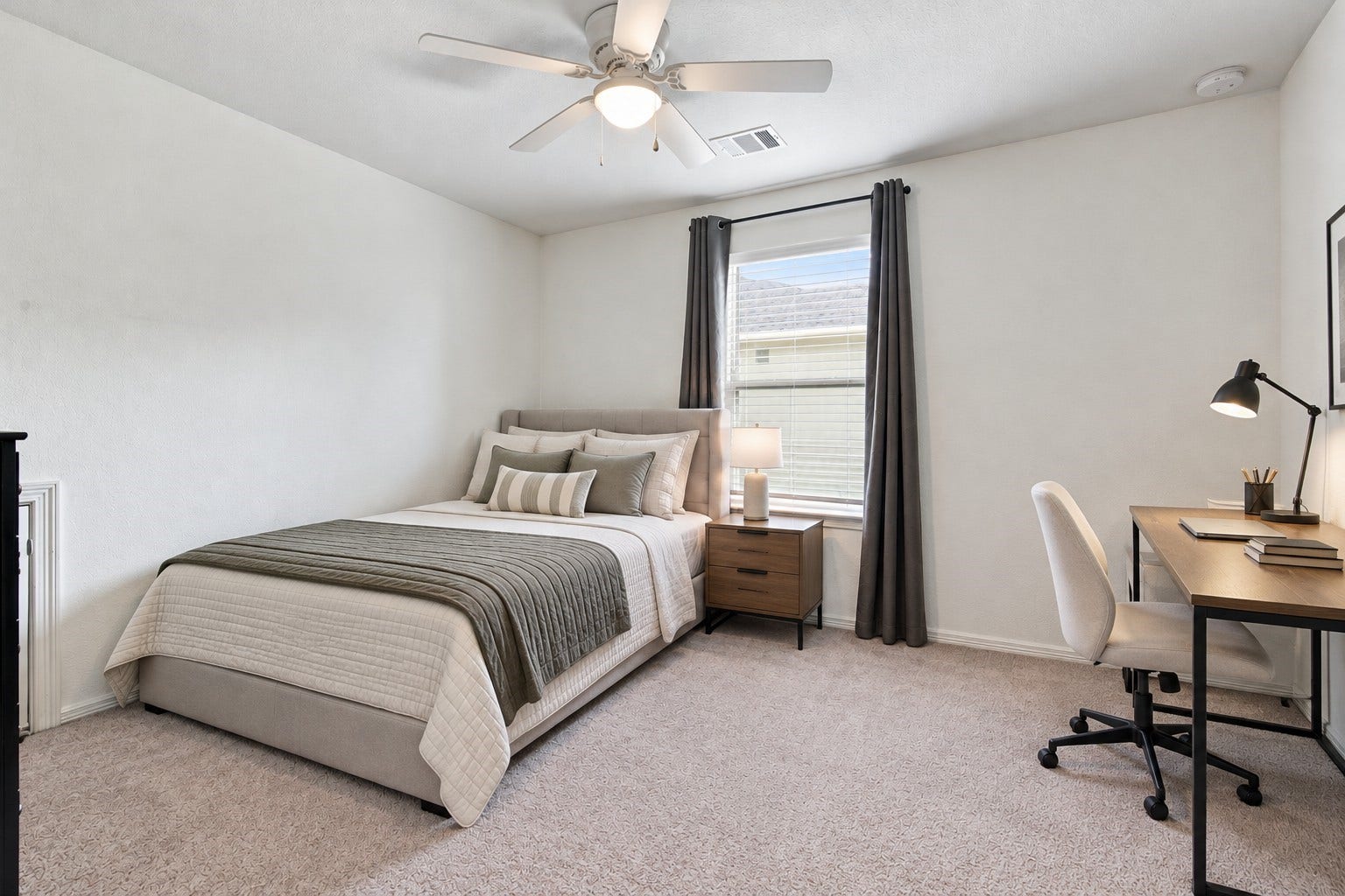14424 Sunny Bend Way, Conroe, TX 77303 Virtually Staged: This secondary bedroom offers a bright, spacious layout with a modern design and soothing neutral tones. Crisp white walls, soft carpeting, and a large window with elegant gray curtains and white blinds create an airy atmosphere filled with natural light. A dedicated workspace area provides an ideal setting for studying or working from home.
