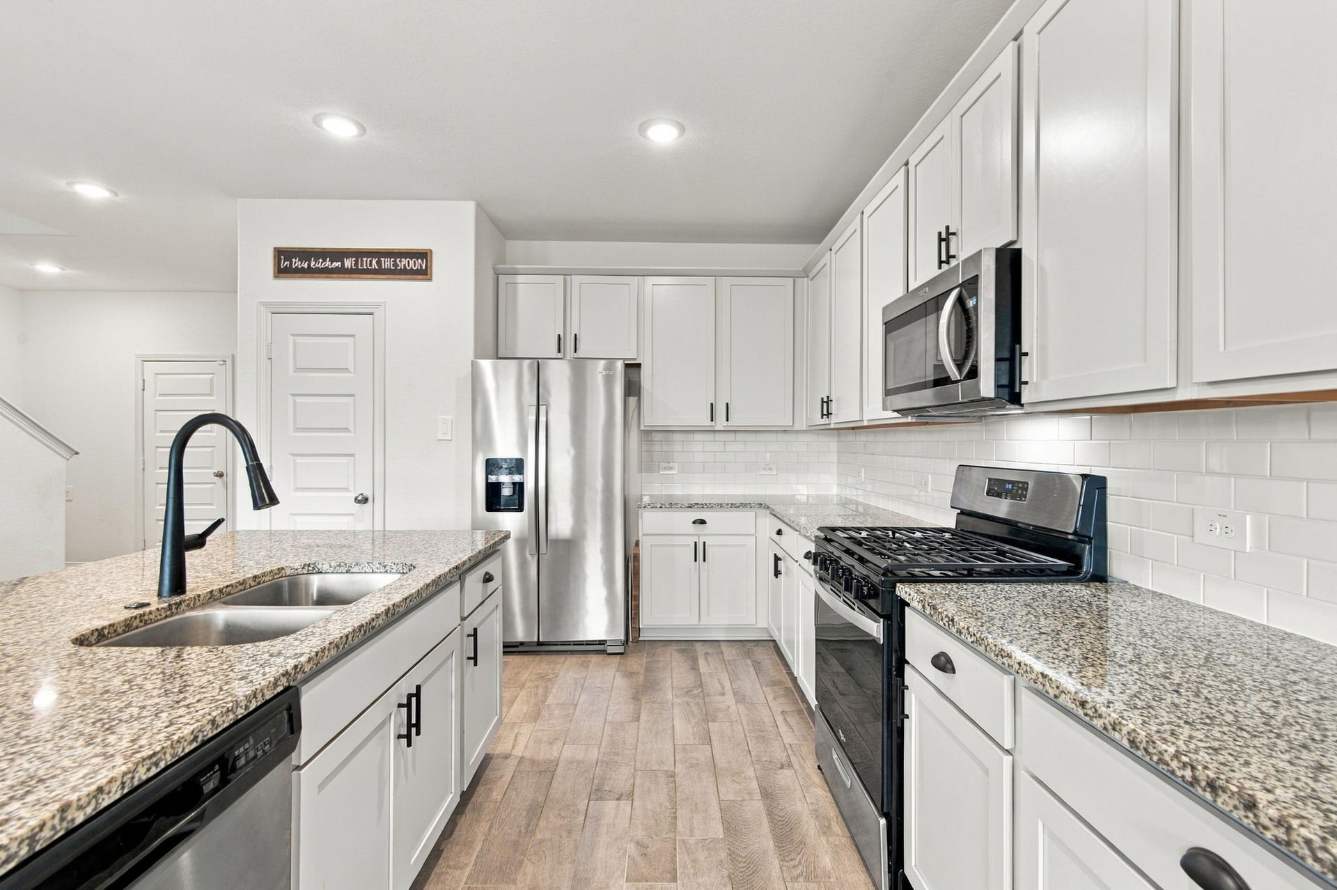 14424 Sunny Bend Way, Conroe, TX 77303 Abundant upper and lower cabinetry provides excellent storage, while recessed ceiling lighting and durable wood-look tile flooring complete this inviting space, perfect for everyday cooking and entertaining.