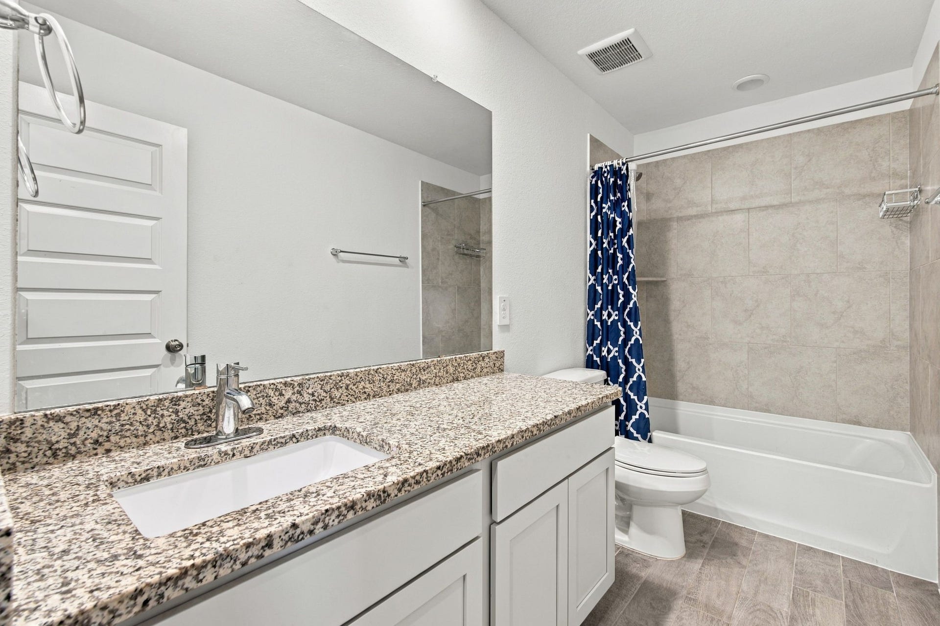 14424 Sunny Bend Way, Conroe, TX 77303 This bright and spacious full bathroom features a clean, modern design with crisp white cabinetry, beautiful speckled granite countertops, and a generous vanity offering ample counter space and storage. The shower and bathtub combination features large-format neutral-toned tile surrounds, creating a stylish and low-maintenance bathing space.