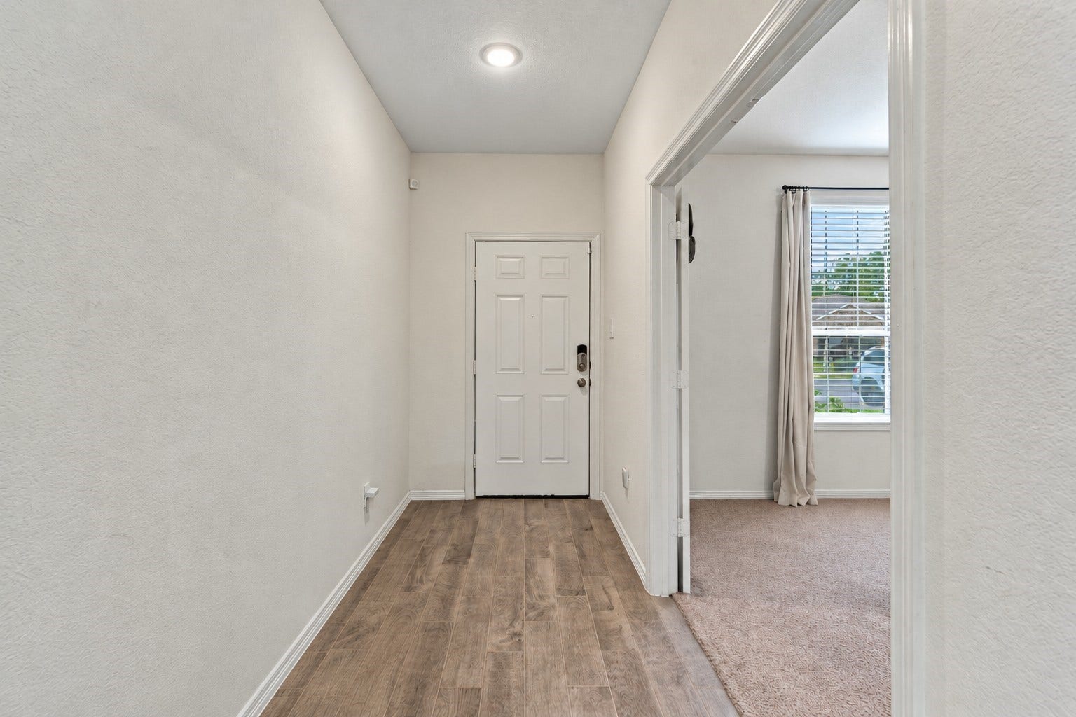 14424 Sunny Bend Way, Conroe, TX 77303 This bright and welcoming entryway features a clean, modern design with soft neutral walls, rich wood-look flooring, and crisp white baseboards.