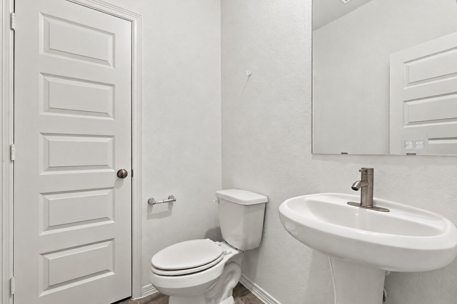 14424 Sunny Bend Way, Conroe, TX 77303 This charming half bath features a clean, modern design with crisp white textured walls and stylish wood-look tile flooring.