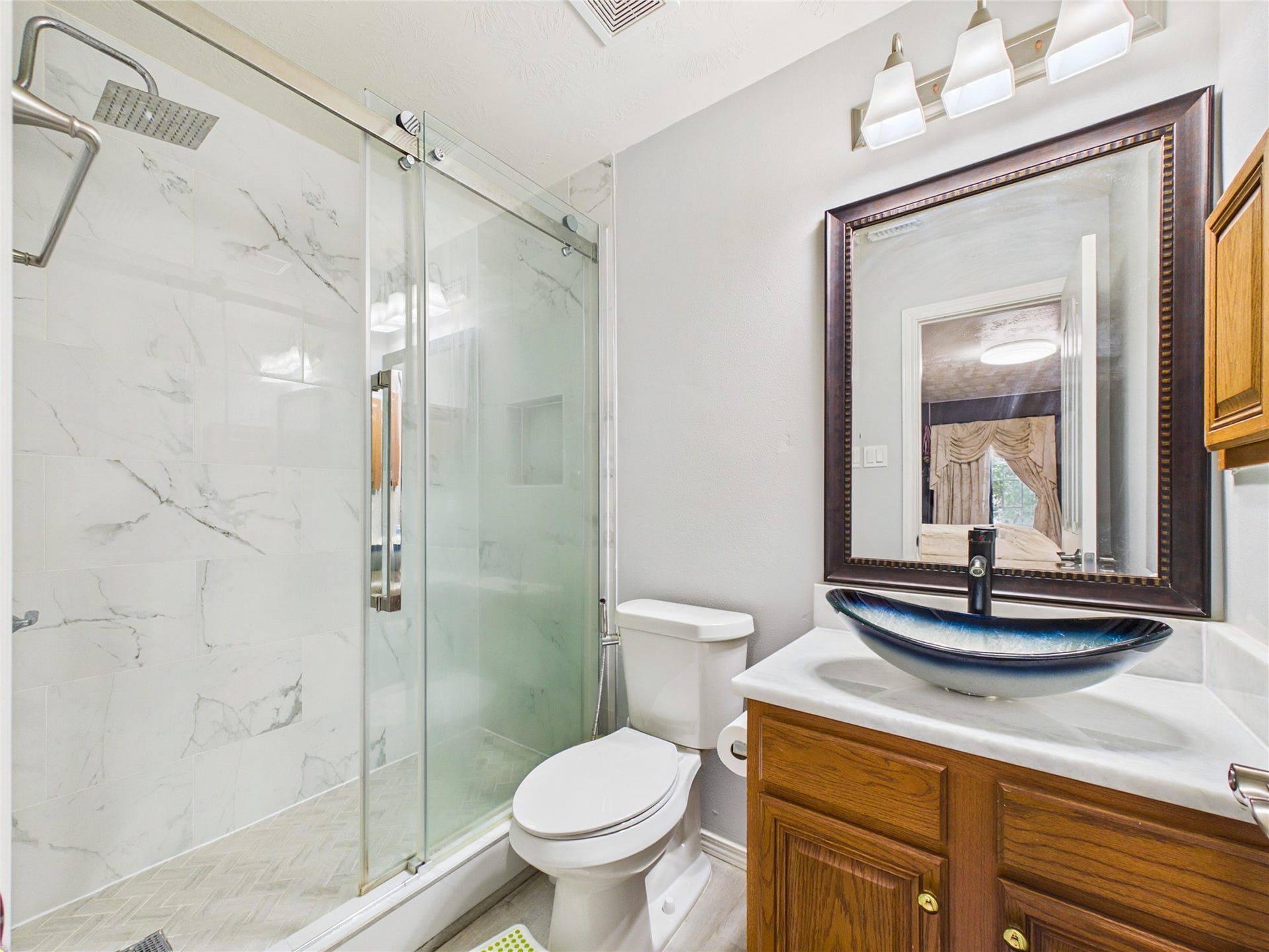 Elegant bathroom featuring a sleek glass-enclosed shower with marble tile, a modern vessel sink, and stylish lighting fixtures.