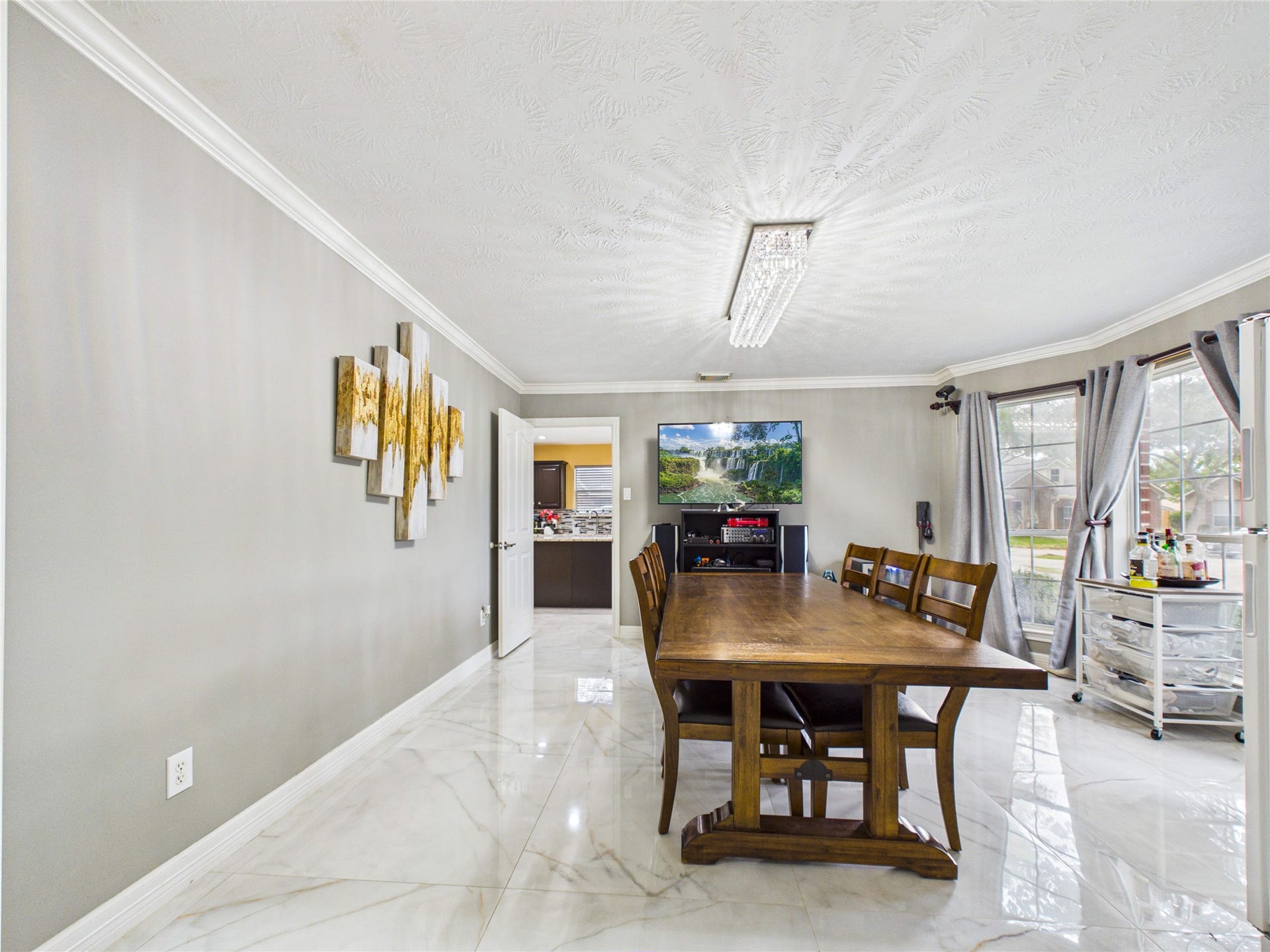 Elegant dining area with a long wooden table, modern light fixture, and large windows for natural light.