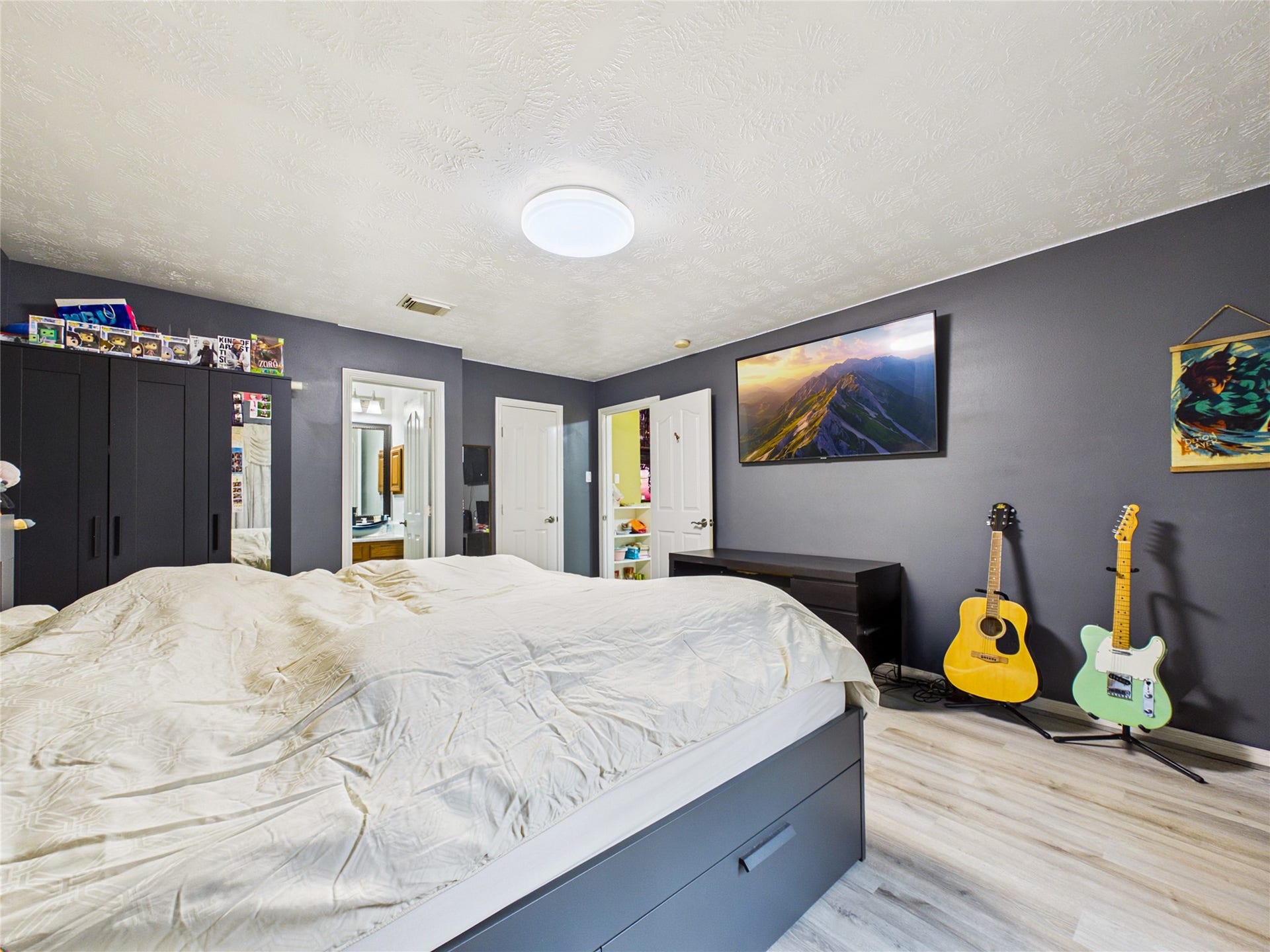 Spacious bedroom with modern dark walls, featuring a cozy bed, sleek wardrobes, and vibrant decor.