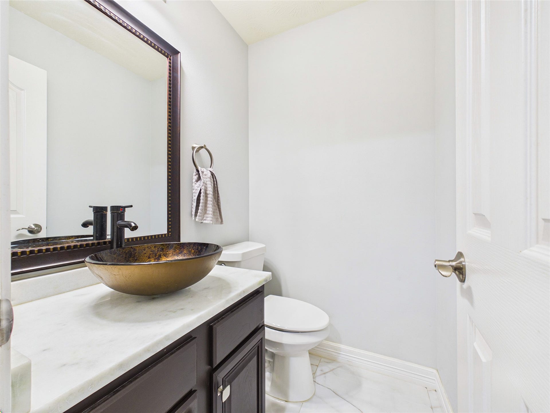 Elegant powder room featuring a stylish vessel sink, marble countertop, and modern fixtures.