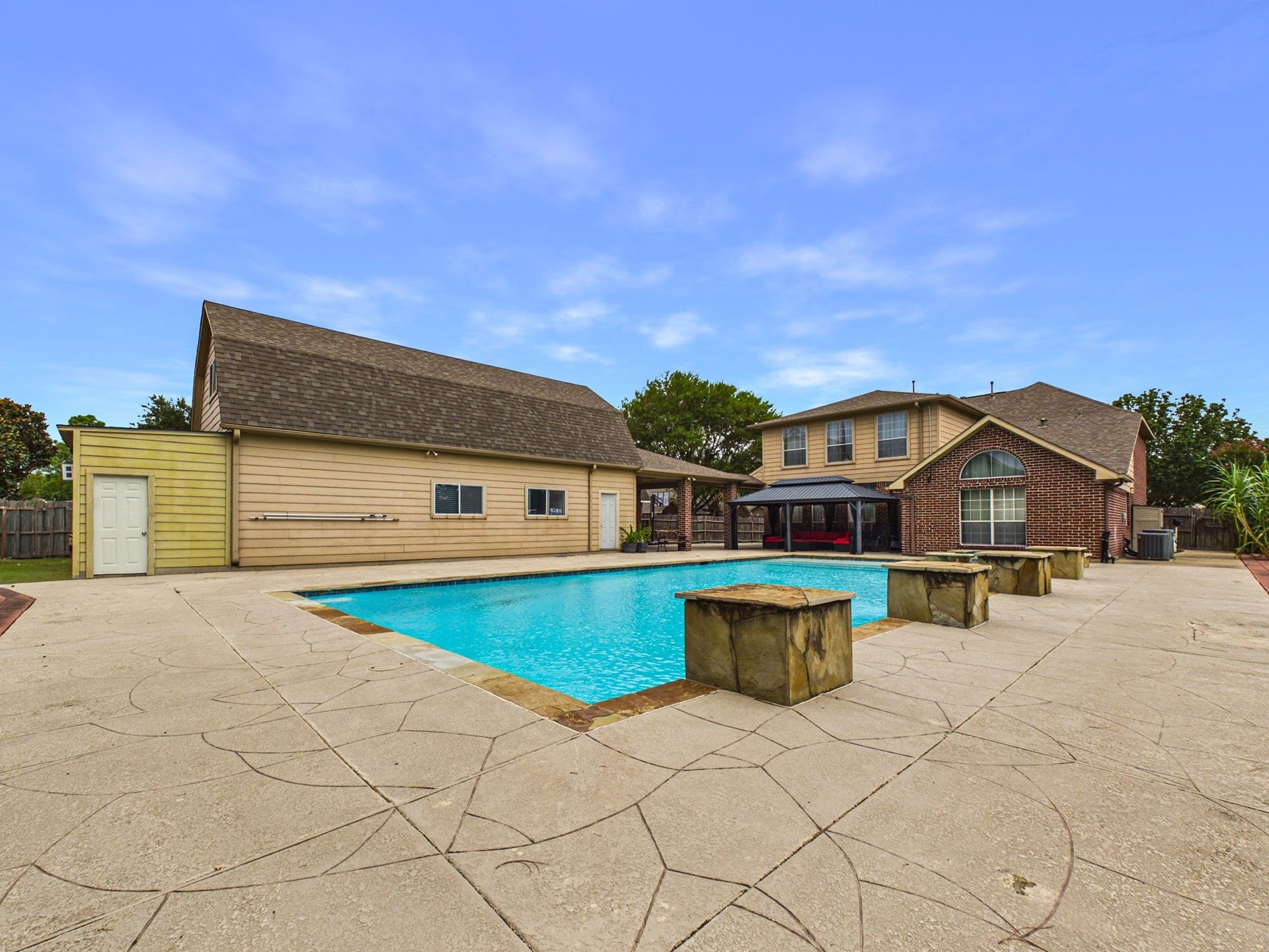Spacious backyard oasis featuring a large swimming pool, expansive patio, and charming two-story home perfect for entertaining and relaxation.