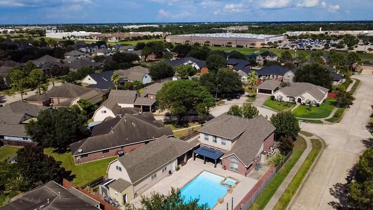 Spacious suburban neighborhood featuring well-maintained homes with lush greenery. Highlighting a property with a private backyard pool, perfect for relaxation and entertaining.