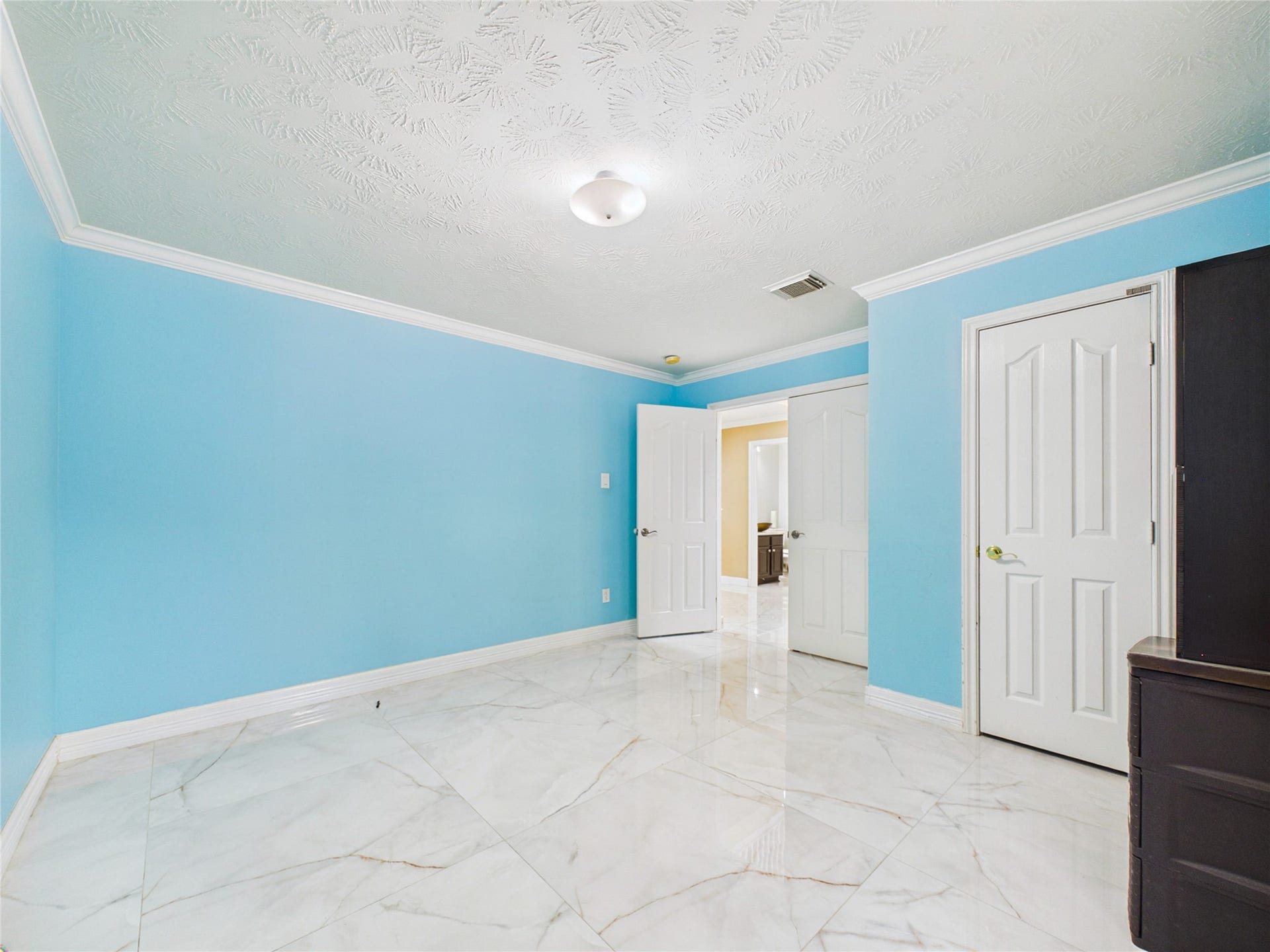 Bright and inviting room with sky-blue walls, elegant white trim, and sleek marble flooring, offering a modern and serene atmosphere.