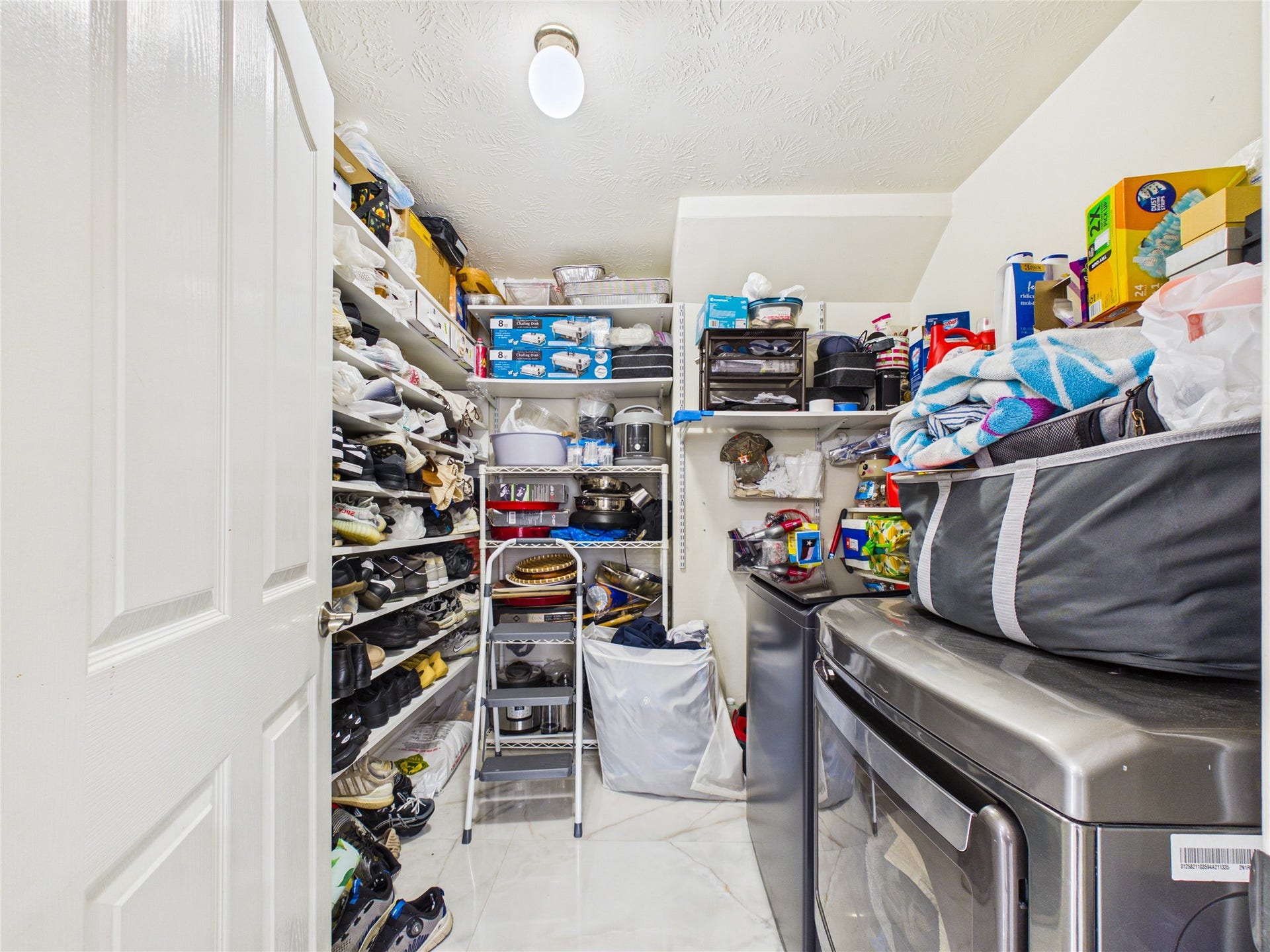 Spacious laundry room with ample shelving for storage, featuring modern appliances and organized shelving for all your essentials.