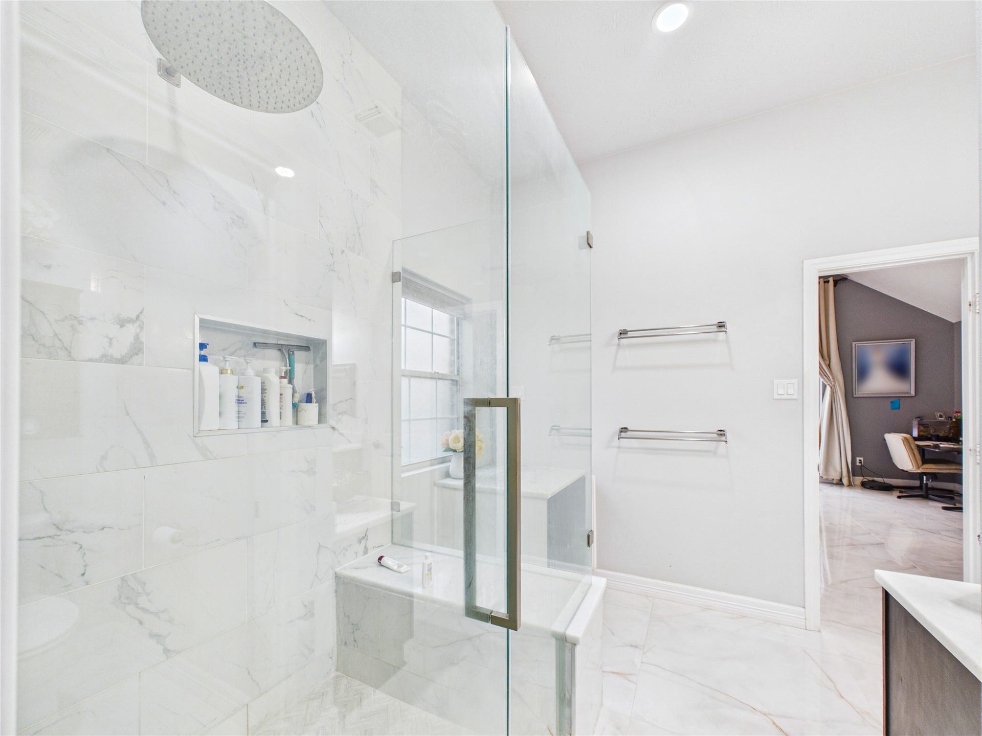 Luxurious bathroom featuring a spacious glass-enclosed shower with elegant marble tile and a rainfall showerhead.