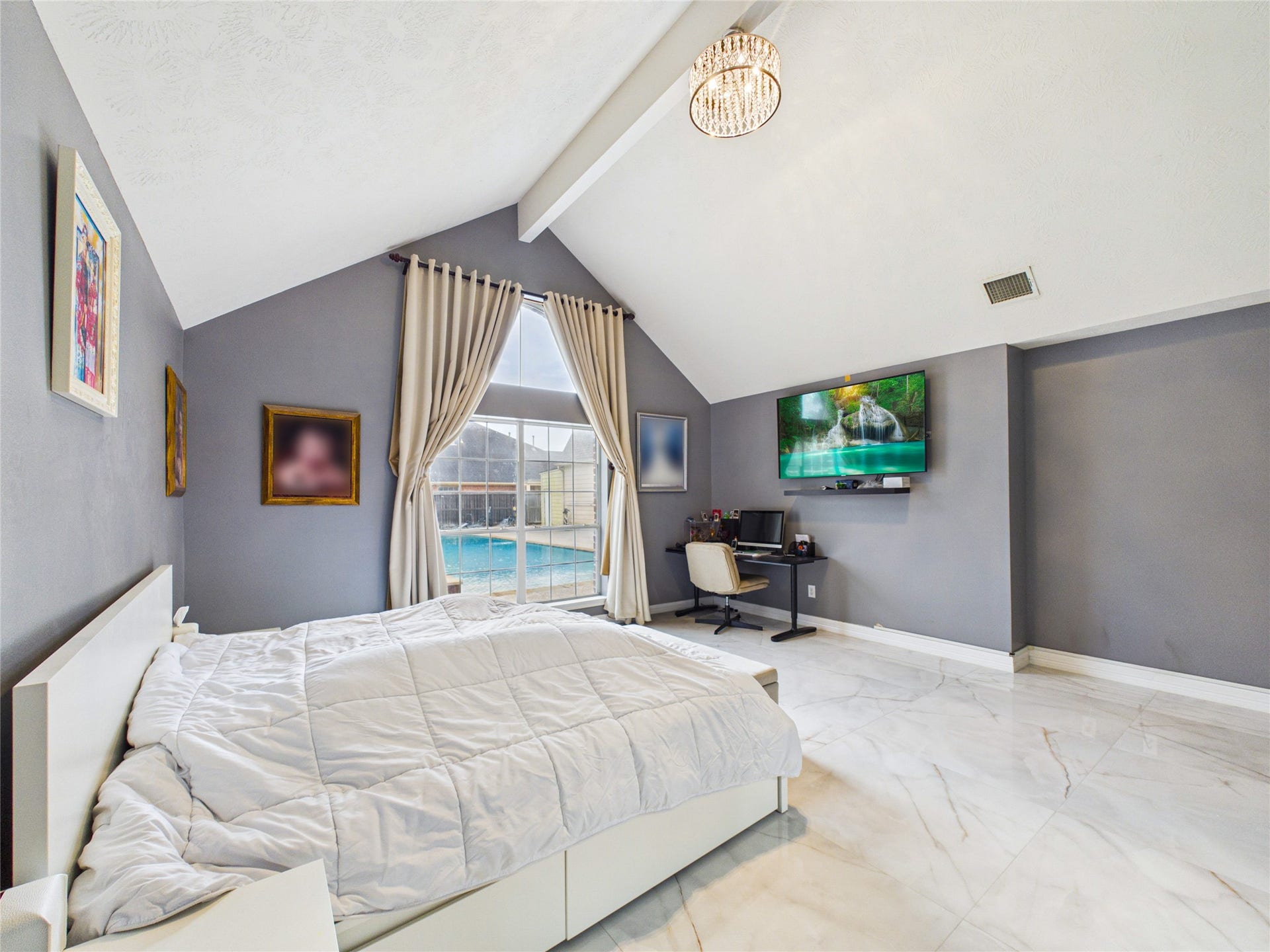 Spacious bedroom with vaulted ceilings, featuring a large window offering views of the pool. The room includes a cozy bed, modern decor, and a convenient workspace, creating a perfect blend of comfort and functionality.