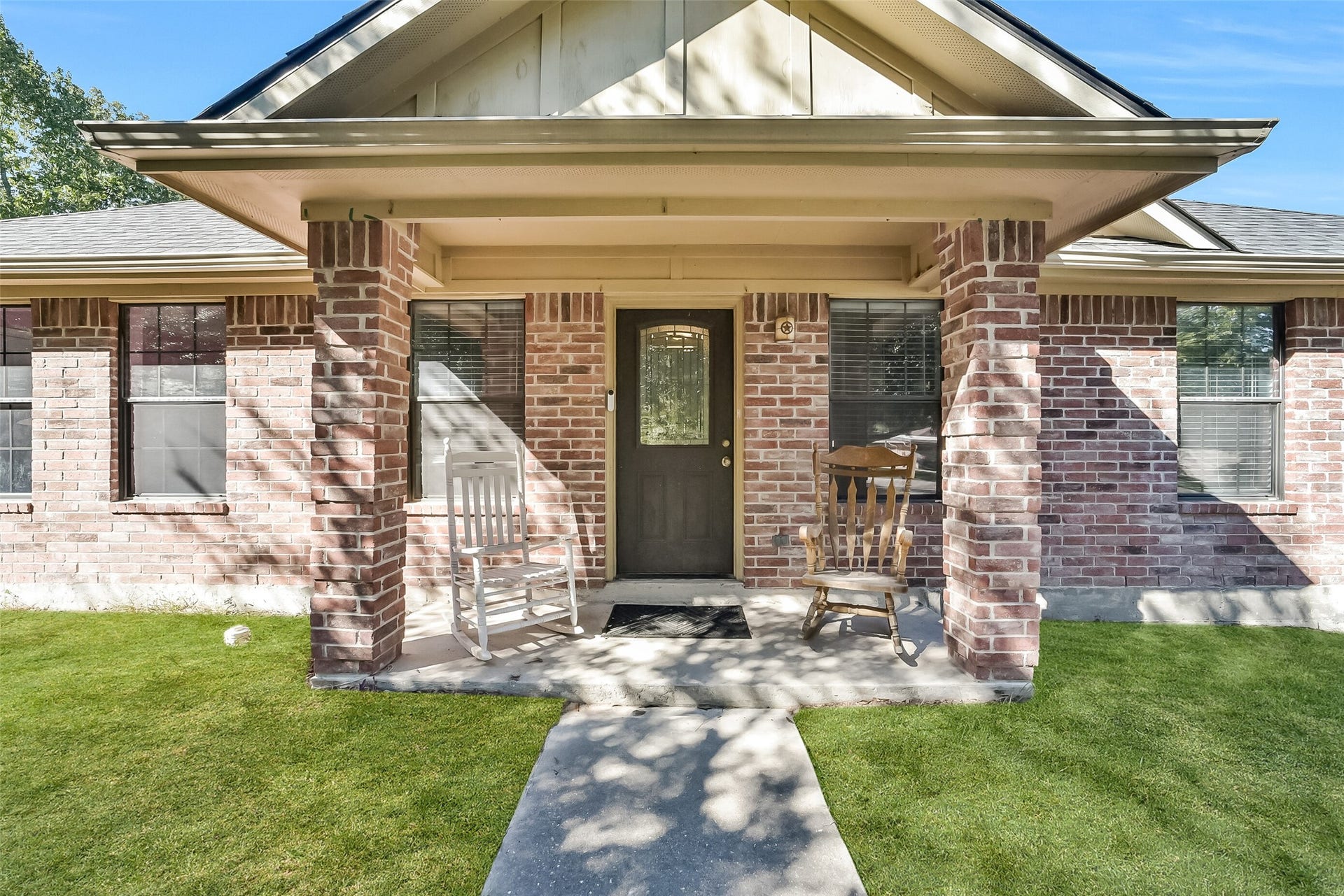 22911 Keith Drive, New Caney, TX 77357 This charming one-story home showcases a classic brick elevation with a welcoming covered front porch framed by substantial brick columns. A decorative glass front door adds character, while the shaded porch offers an inviting spot to relax and enjoy your morning coffee.