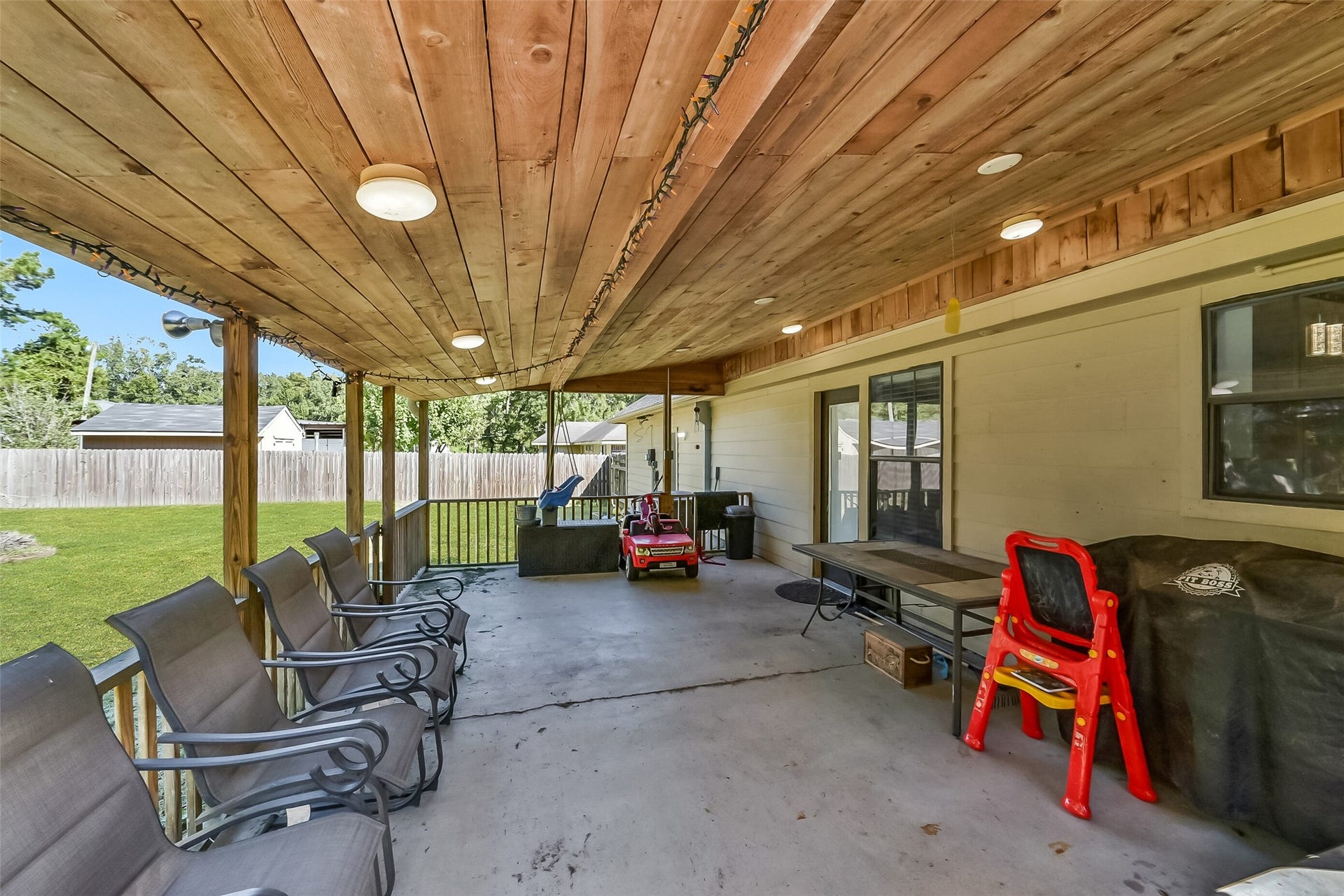 22911 Keith Drive, New Caney, TX 77357 Enjoy outdoor living on this spacious covered patio, featuring a wood-plank ceiling, overhead lighting, and views of the large fenced backyard. With ample room for dining, relaxing, and entertaining, this inviting space offers a shaded retreat just steps from the home.