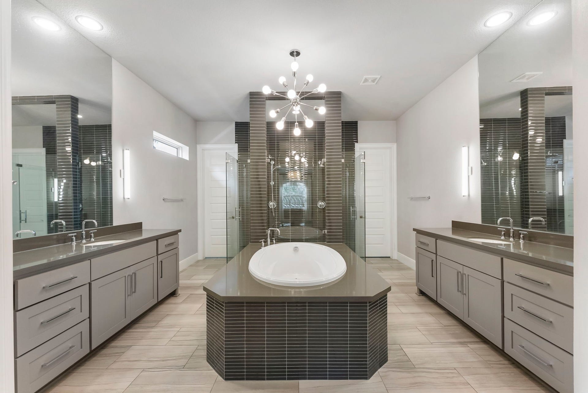 Primary bathroom featuring custom lighting, dual sinks, and abundant cabinetry.