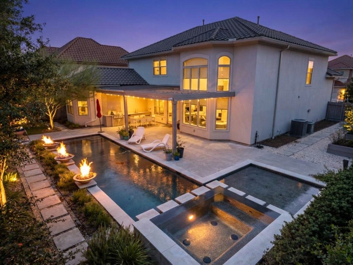 Inviting outdoor living space showcasing a pristine pool, spa, and a fully equipped outdoor kitchen