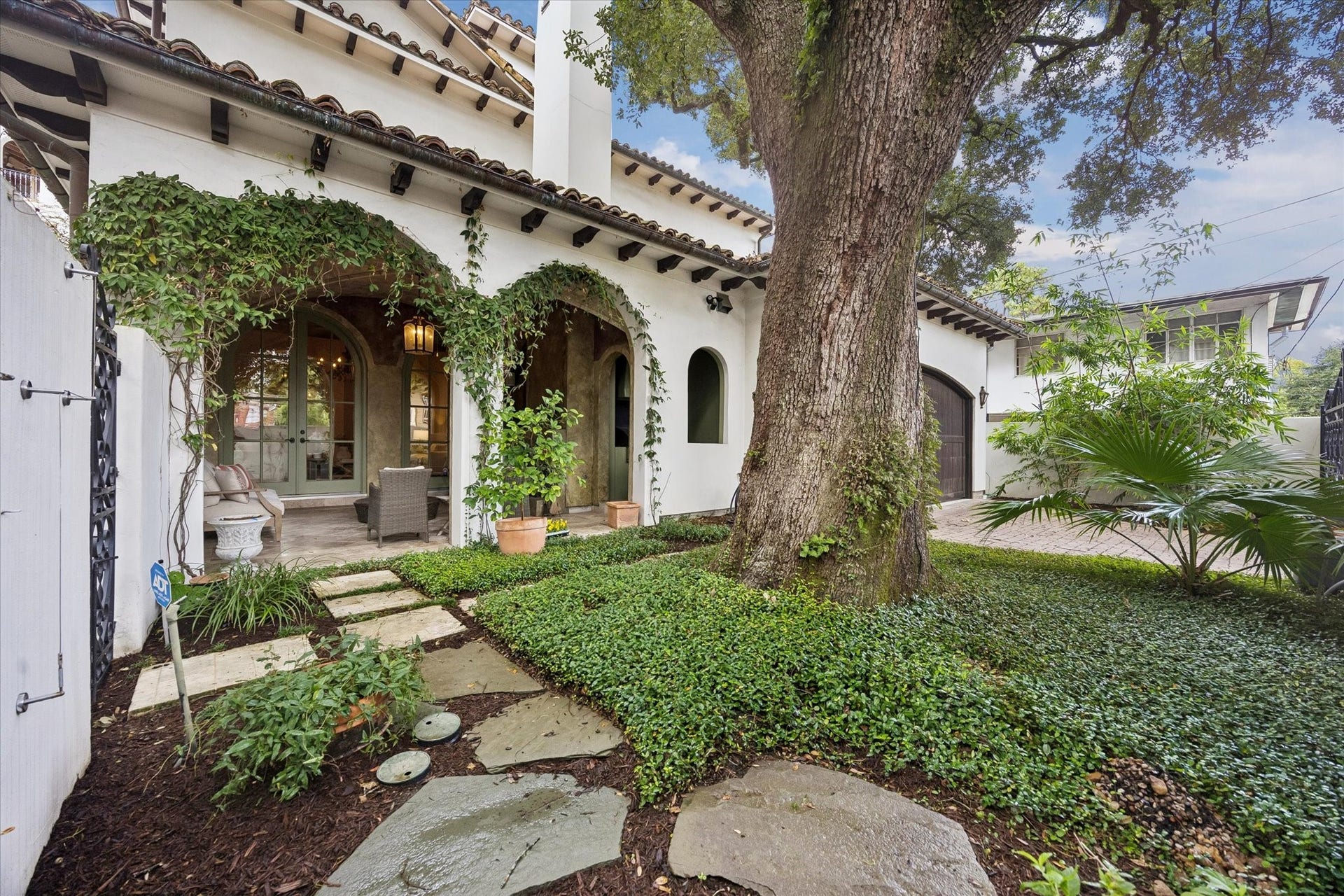 5120 Mt Vernon, Houston, TX 77006 The huge oak tree in the yard shades the patio and the rest of the house. Driveway can be glimpsed behind the palm.