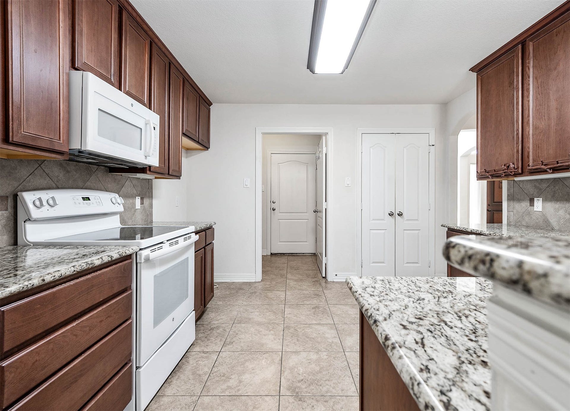 Discover a spacious kitchen brimming with granite counters, a walk-in pantry, and seamless access to the utility room and garage, perfect for effortless living.