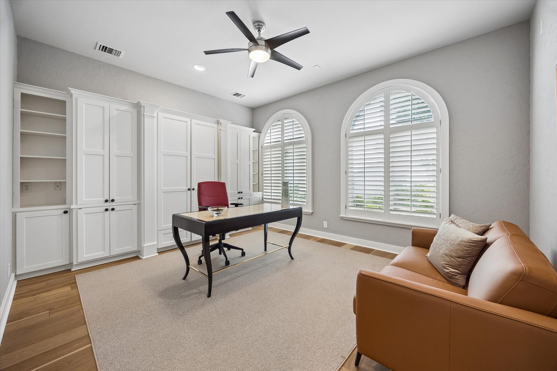 Downstairs study or secondary bedroom with built-in's, arched windows with shutters, closer and hardwood floors.