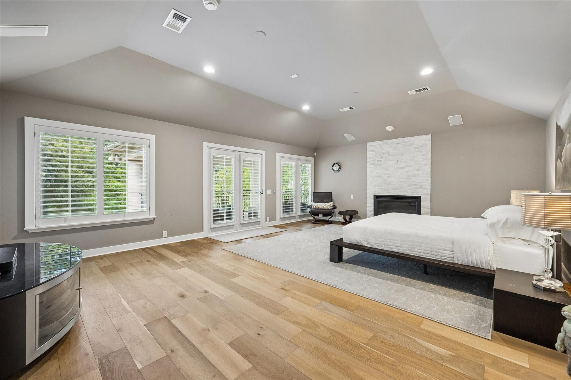 Large windows and French doors lead out to a covered balcony with verdant views.