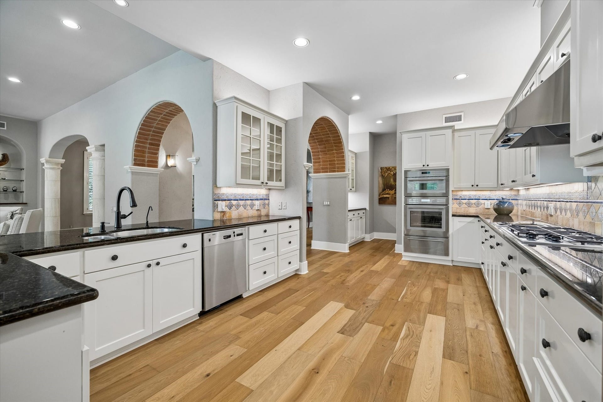 Galley view of the chef's kitchen with stainless steel appliances including an in-counter steamer, double ovens, gas cooktop, dishwasher, 100+ bottle wine chiller and built-in fridge.