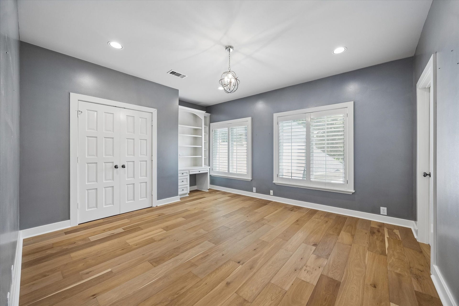 Ensuite secondary bedroom with built-in desk and hardwood floors.