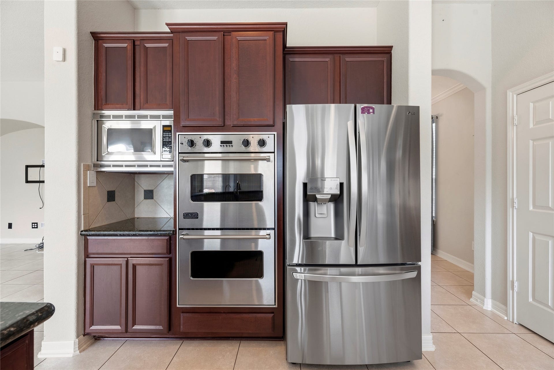 3707 Cat Springs Lane, Missouri City, TX 77459 This high-performance kitchen wall is anchored by a suite of stainless steel appliances, including a professional-grade Viking double oven and a built-in microwave. Rich, dark wood cabinetry provides a classic contrast, offering plenty of storage.