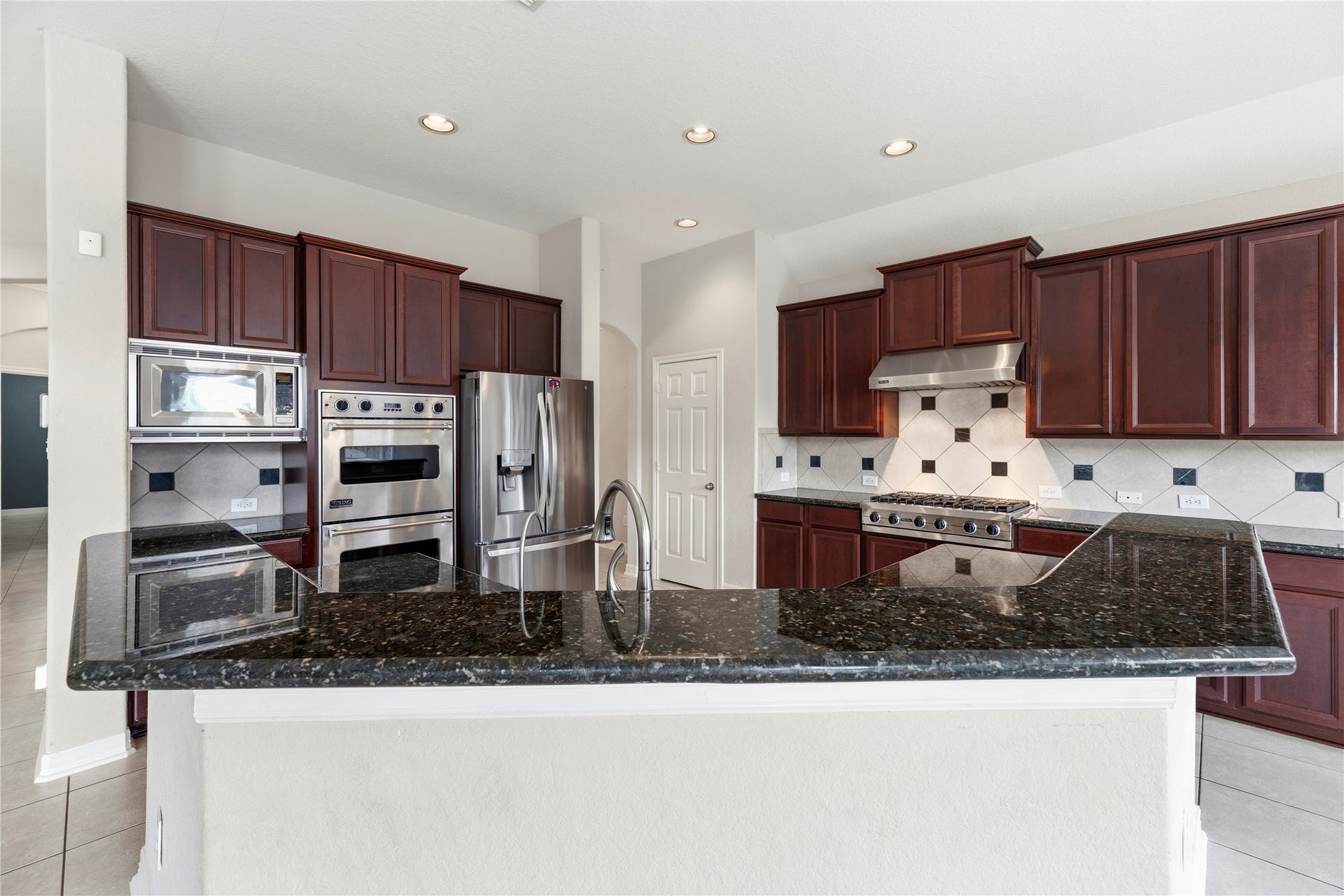 3707 Cat Springs Lane, Missouri City, TX 77459 This high-end kitchen is a chef's delight, featuring granite countertops and a large central island. The built-in breakfast bar provides a casual spot for morning coffee or a perfect hub for social gatherings.
