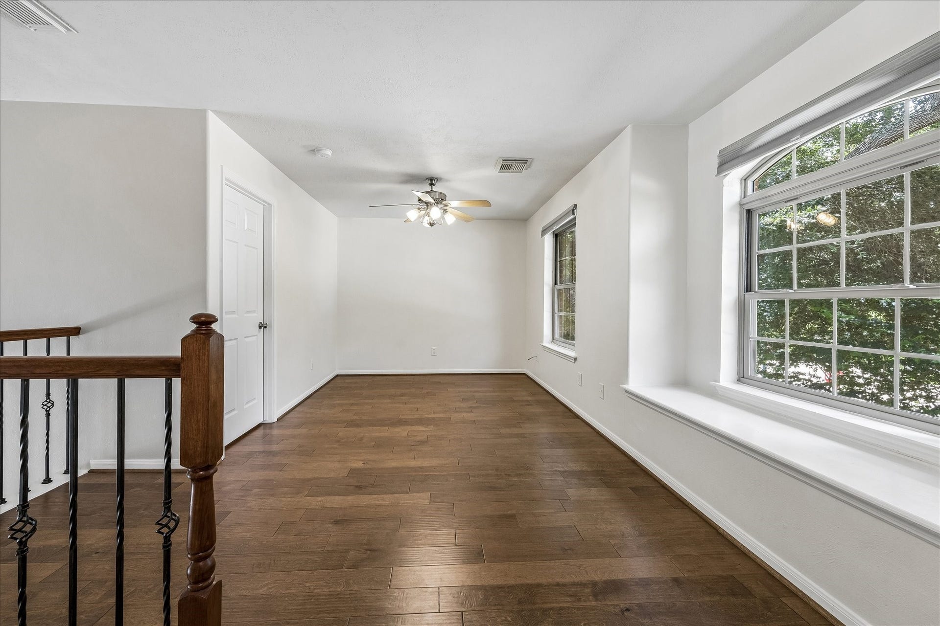 Comfortable secondary bedroom with vaulted ceilings and warm hardwood floors.