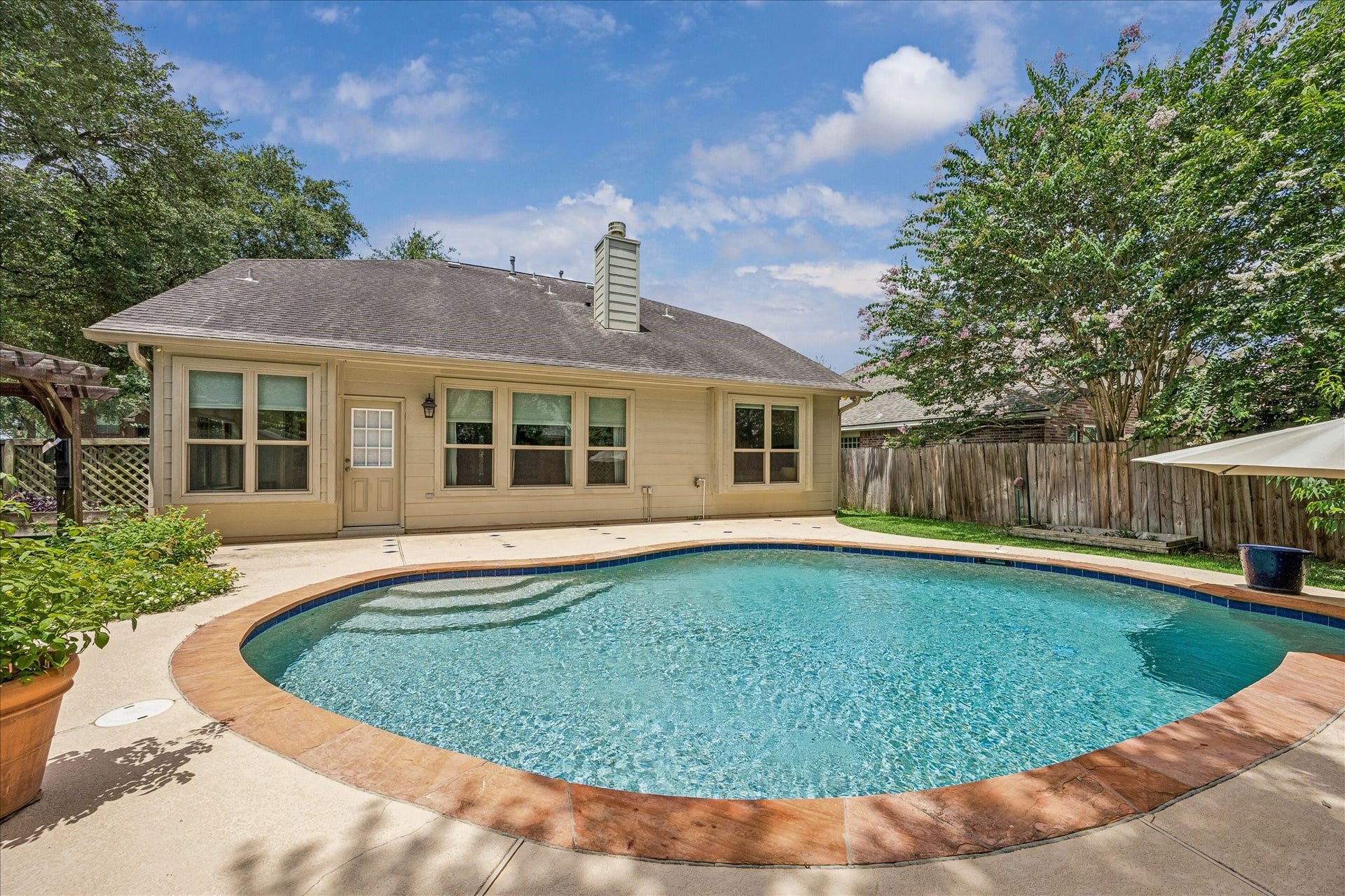 Private backyard retreat featuring a sparkling pool, expansive patio, mature landscaping, and plenty of room for entertaining.