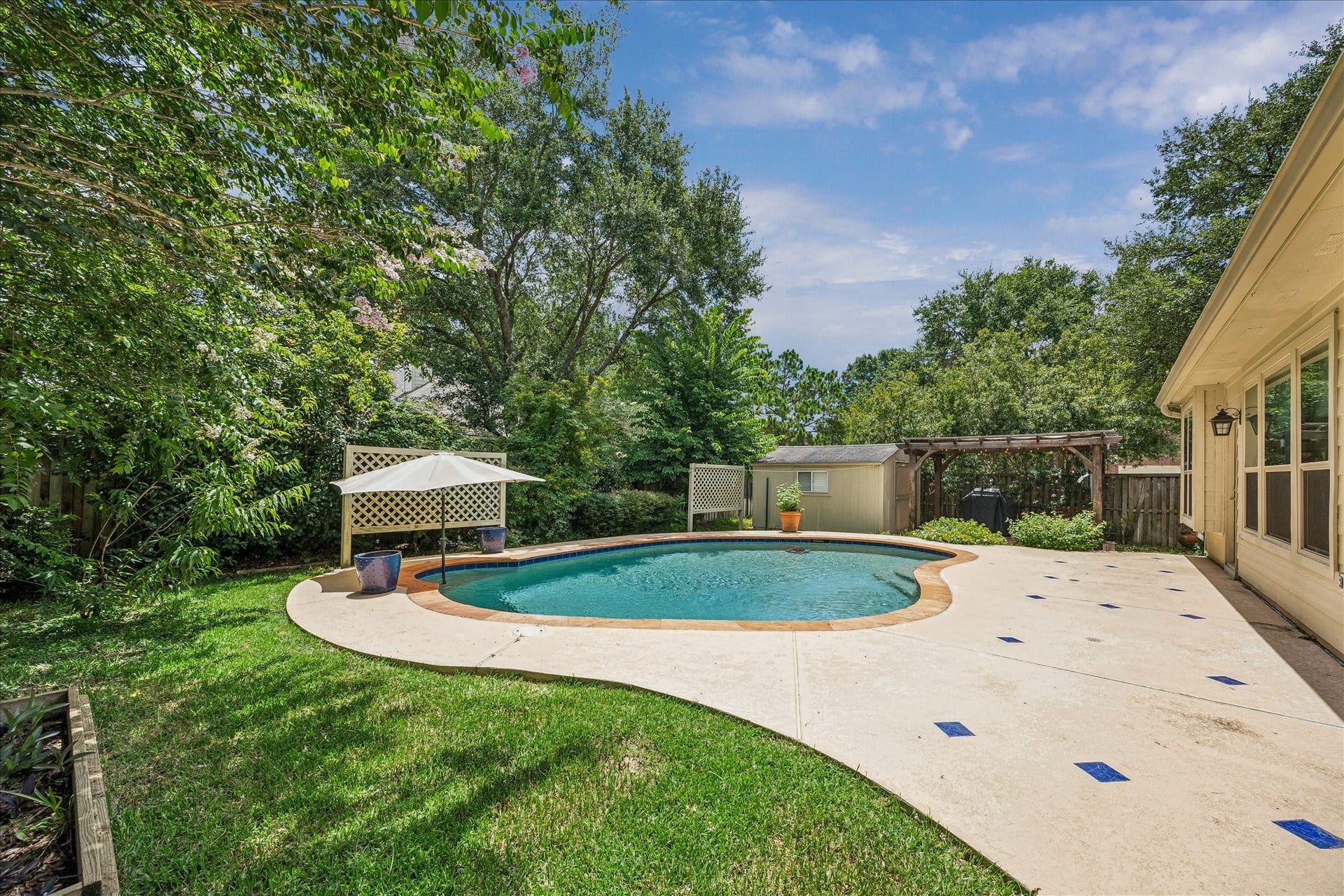 Enjoy shaded poolside lounging beneath the pergola while taking in views of the backyard retreat.