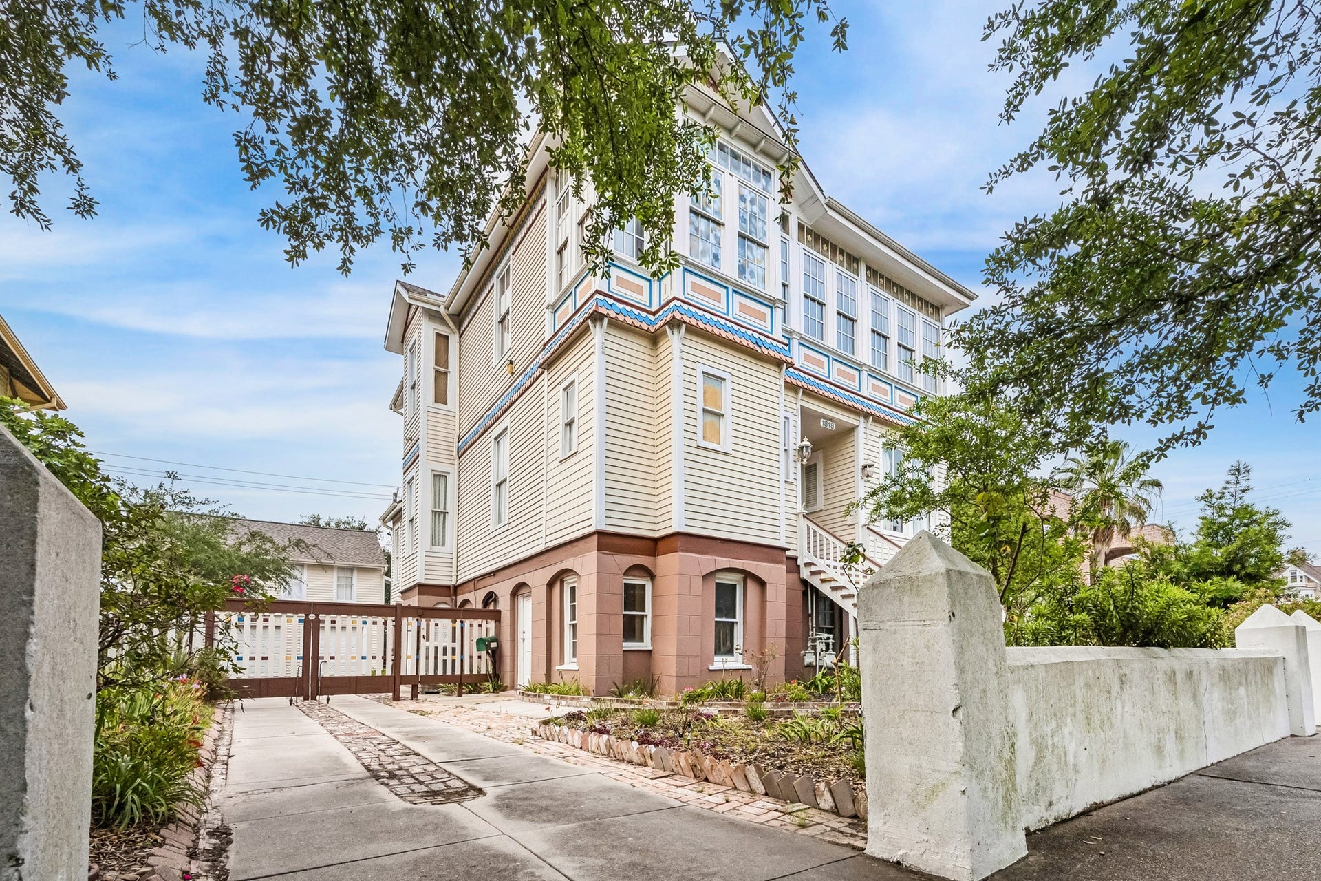1818 Broadway Street, Galveston, TX 77550 Long driveway with a delightful wooden access gate providing extra security. The white stone fence at the front ofd the home is original.