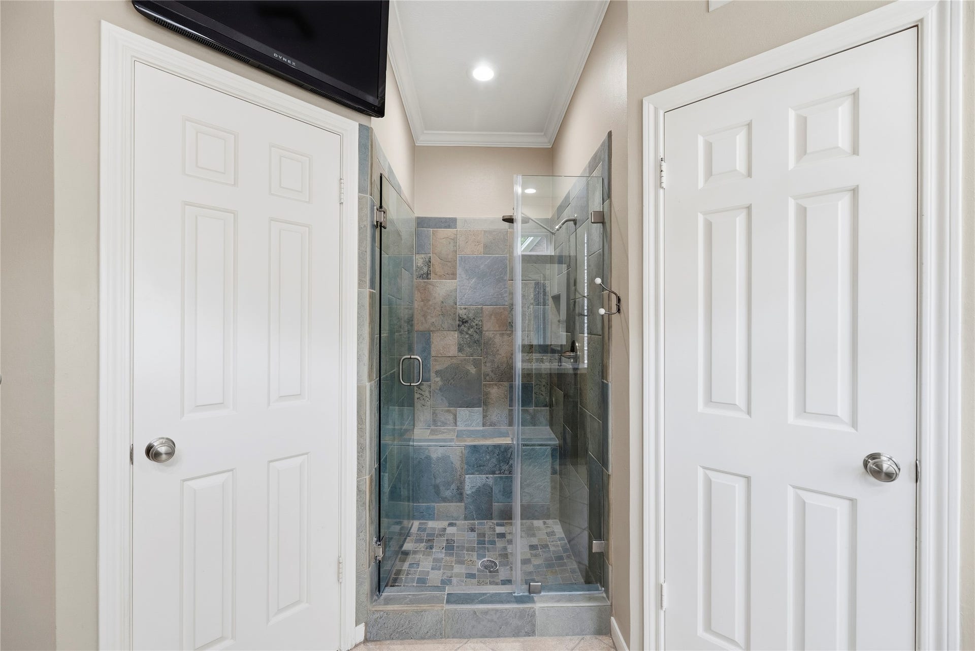 Primary bathroom featuring a sleek glass-enclosed shower flanked by two spacious walk-in closets.