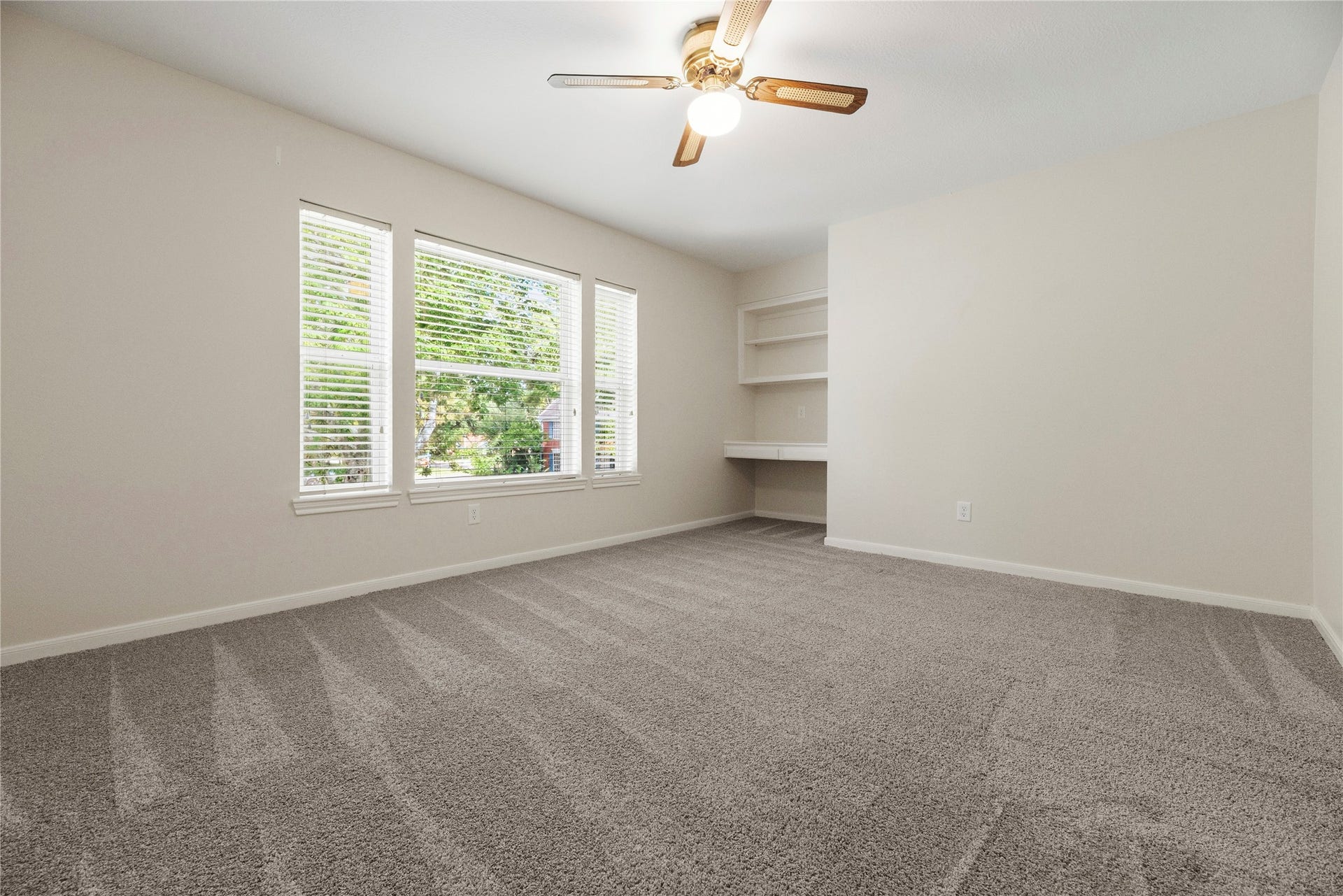 The fourth bedroom with plush carpeting (upgraded pad and carpet replaced in 2022) and a built-in desk with shelving.