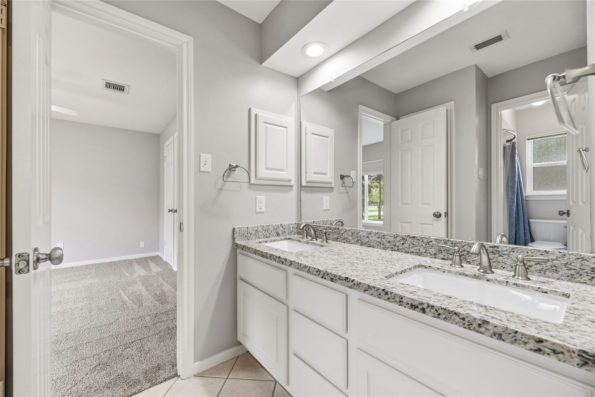 A Jack-and-Jill-style bathroom featuring a dual-sink vanity with granite countertops.