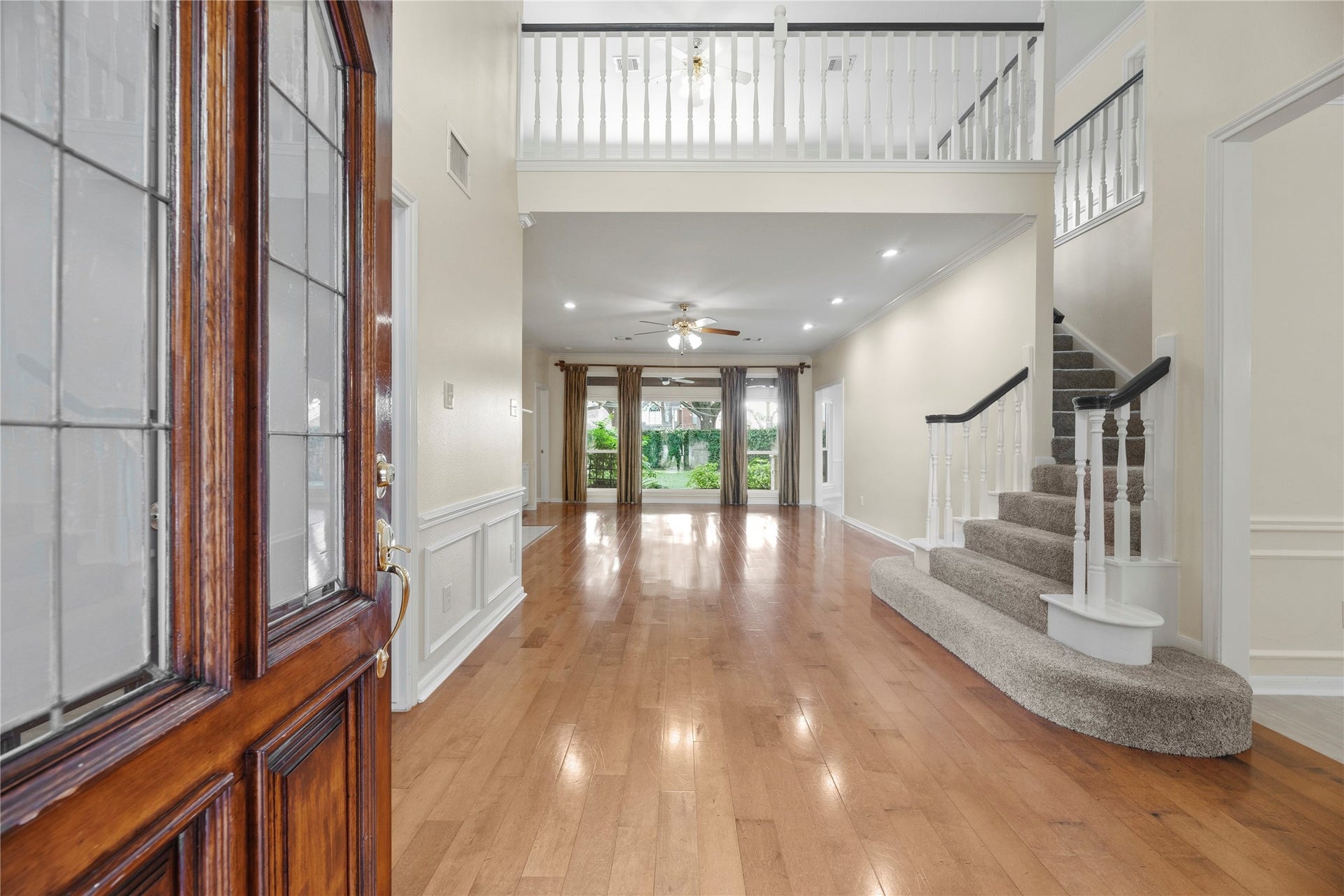 Inviting entryway with engineered hardwood floors and abundant natural light flowing from large windows overlooking lush backyard.