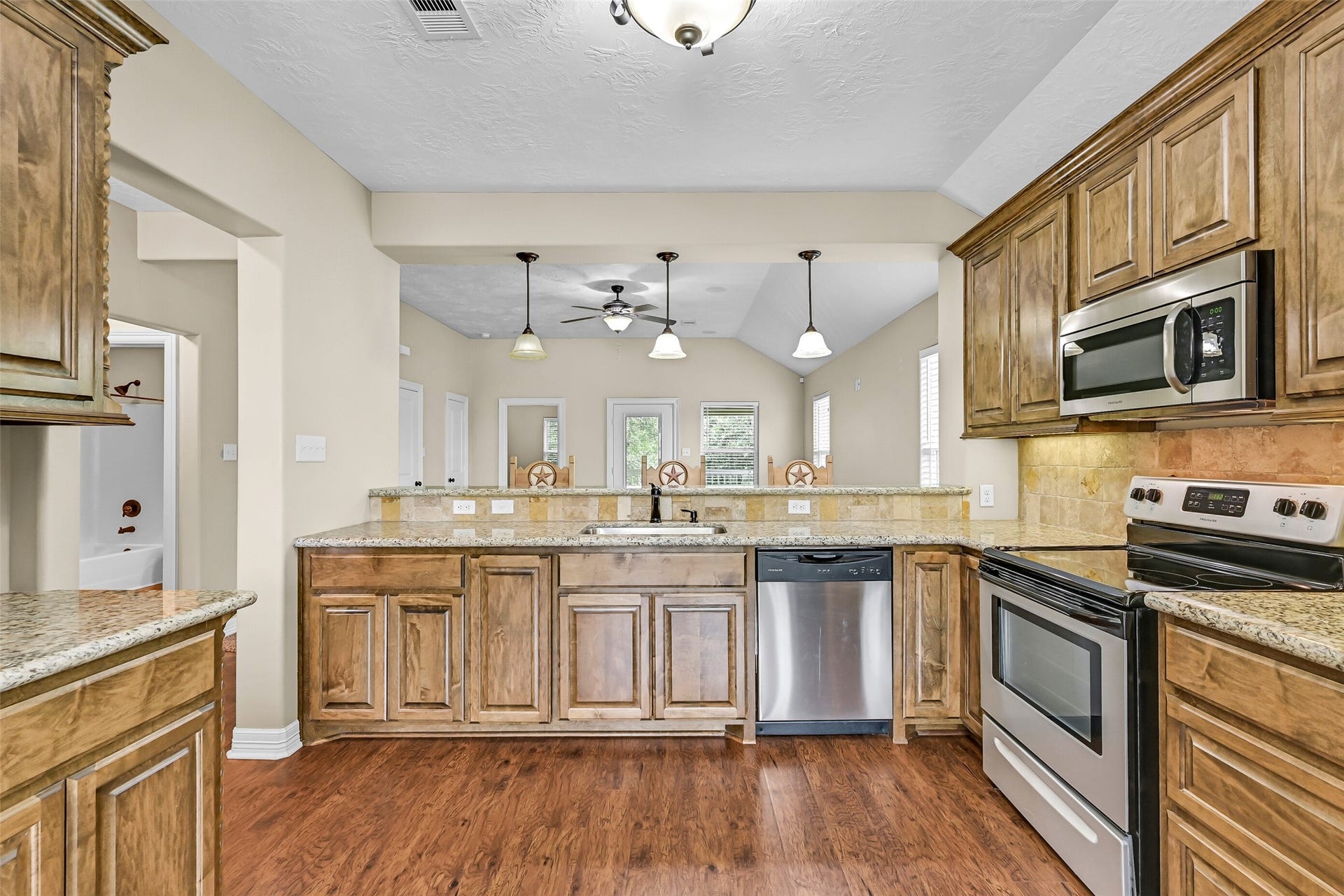 11930 Bastrop Beach Road, Angleton, TX 77515 Designed with both everyday living and entertaining in mind, the spacious kitchen offers abundant cabinet storage, generous granite prep space, an undermount sink, bartop seating, and an open view into the vaulted family room.
