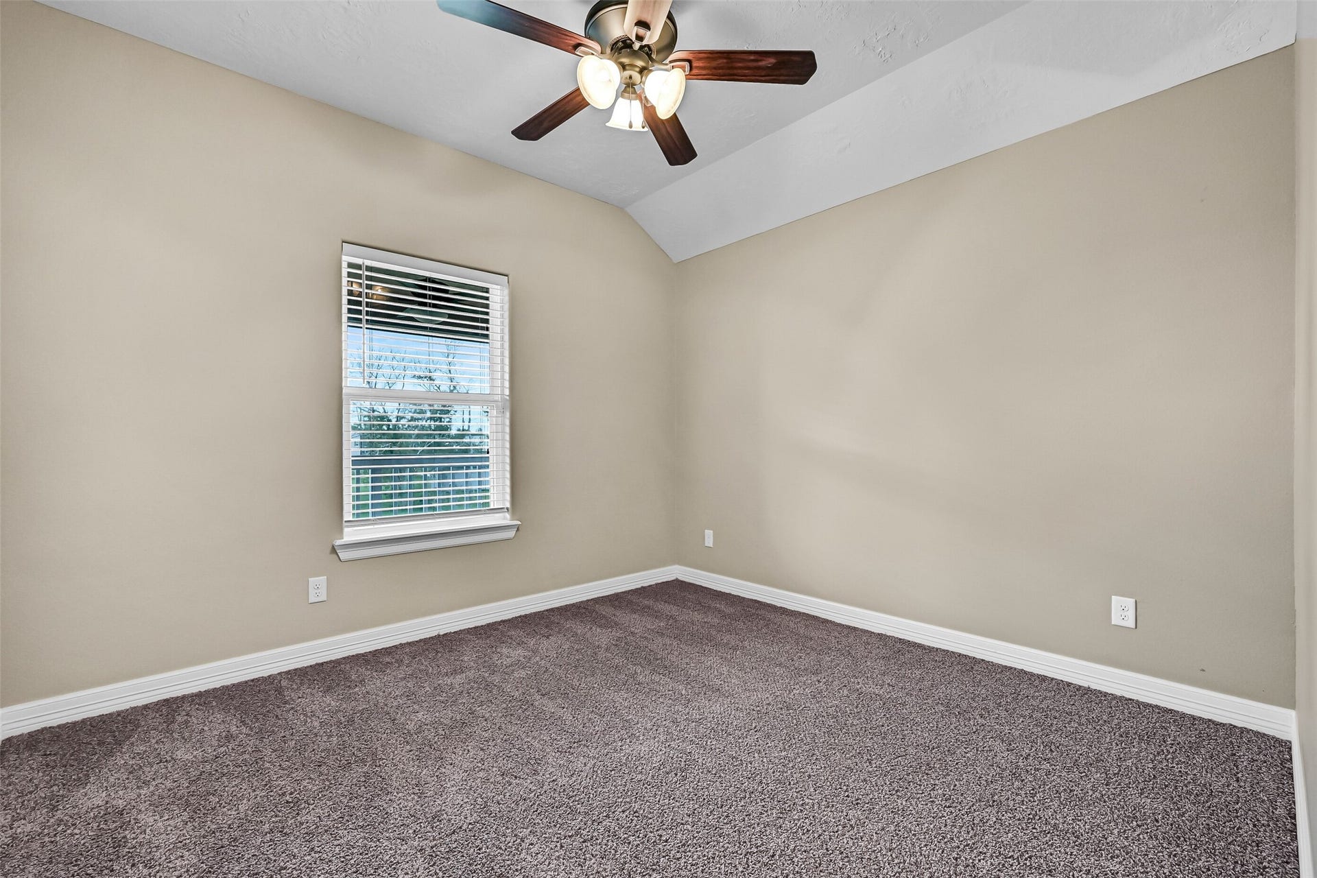 11930 Bastrop Beach Road, Angleton, TX 77515 One of two generously sized secondary bedrooms, this inviting space features a vaulted ceiling, lighted ceiling fan, plush carpet, and peaceful views of the surrounding trees.